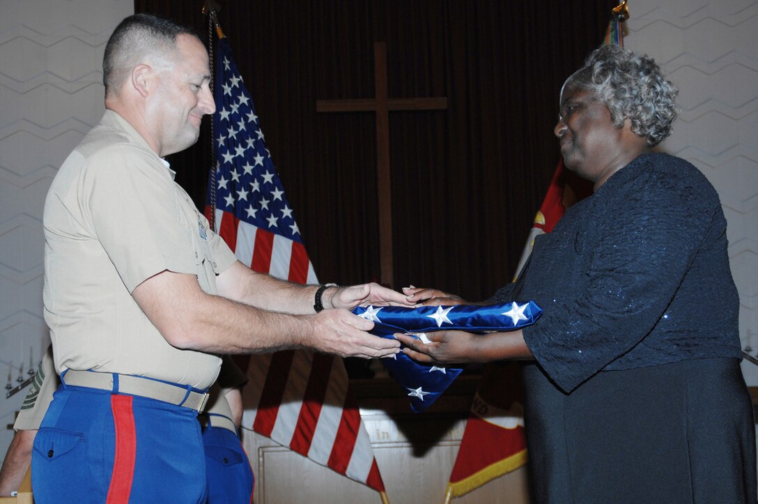 Paula B. Knight, secretary for the Operations Directorate, Marine Corps Logistics Command, receives an American flag, June 26, from Col. Jeffrey Q. Hooks, commander, Marine Depot Maintenance Command, during a retirement ceremony held at the Base Chapel. Knight retired after devoting 36 years to the armed forces as a civil servant.