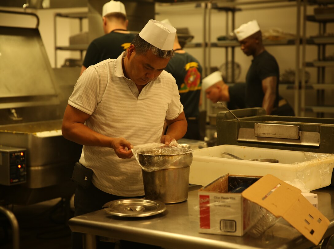 Joseph Chu, owner, Red Lotus restaurant, checks a pot of ingredients during a guest chef event at Phelps Mess Hall, June 30, 2014. Chu visited the hall to help Marines prepare a unique menu of oriental cuisine.