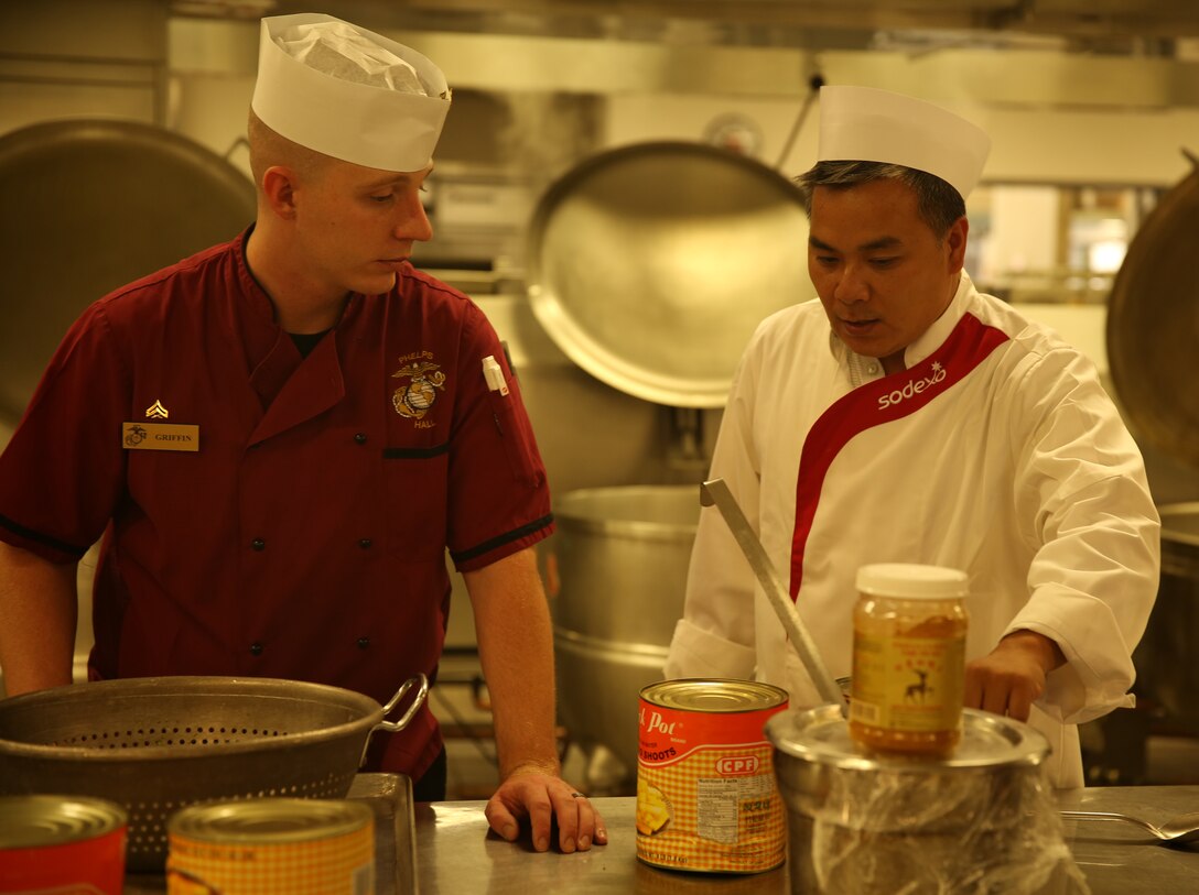 Joseph Chu, owner, Red Lotus restaurant, talks with Cpl. Benjamin Griffin, food service specialist, Headquarters Battalion, during a guest chef event at Phelps Mess Hall, June 30, 2014. The menu prepared during the event was served to Marines whom arrived at the mess hall shortly after.