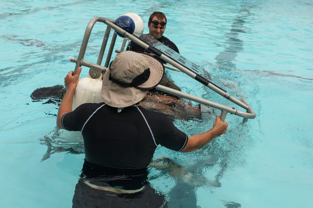 A Japan Ground Self-Defense Force soldier is upended by underwater egress trainers during shallow water egress training (SWET) at Camp Hansen’s pool, June 26. The SWET course covered how to use a breathing regulator and flotation device as well as techniques on how to escape an aircraft while submerged underwater. The involvement of JGSDF soldiers in the MEU’s regularly-scheduled training comes in response to the April 2012 U.S.-Japan Security Consultative Committee, also known as the 2+2, statement calling for the enhancement of bilateral security and defense cooperation. (U.S. Marine Photo by Cpl. Henry J. Antenor)