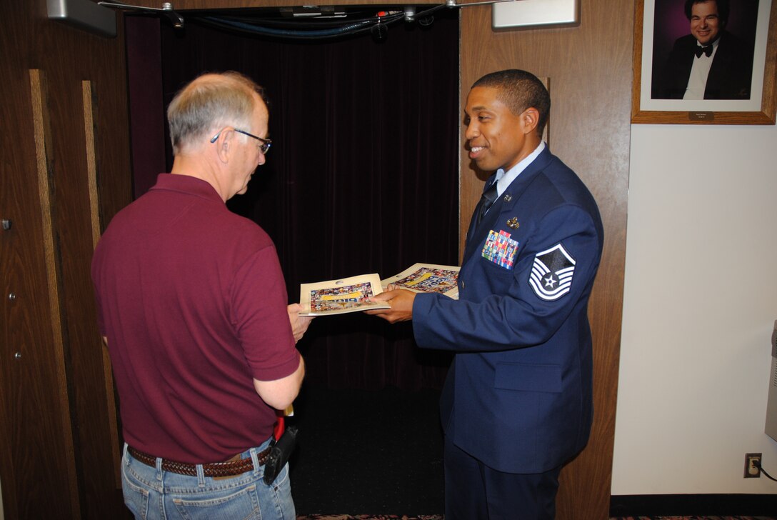 Master Sgt. Kingsley Scott hands a program to a guest attending the Tops in Blue show June 29, 2014, at the Chester Fritz Auditorium in Grand Forks, N.D. The show was Scott's first time seeing Tops in Blue perform live. More than 30 volunteers from Grand Forks Air Force Base helped set up stage equipment and serve as ushers and greeters for the show. (U.S. Air Force photo/Staff Sgt. Luis Loza Gutierrez)