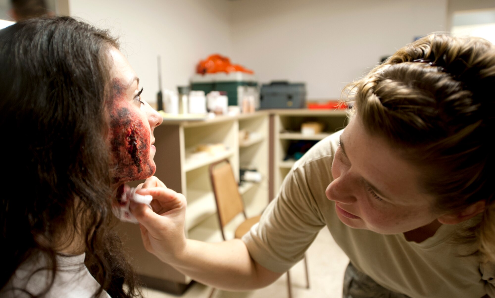 Air Force Master Sgt. Carrie Johnson, 673d Aerospace Medicine Squadron noncommissioned officer-in-charge of community health,  sponges fake blood on Airman Hannah Adams, 673d Logistics Readiness Squadron administrative assistant, during the annual mission assurance exercise on Joint Base Elmendorf-Richardson, Alaska, June 26, 2014. Individuals volunteered to be wounded victims to make the exercise more realistic for the personnel responding on the scene to treat and evacuate those victims. (U.S. Air Force photo/Airman 1st Class Tammie Ramsouer)