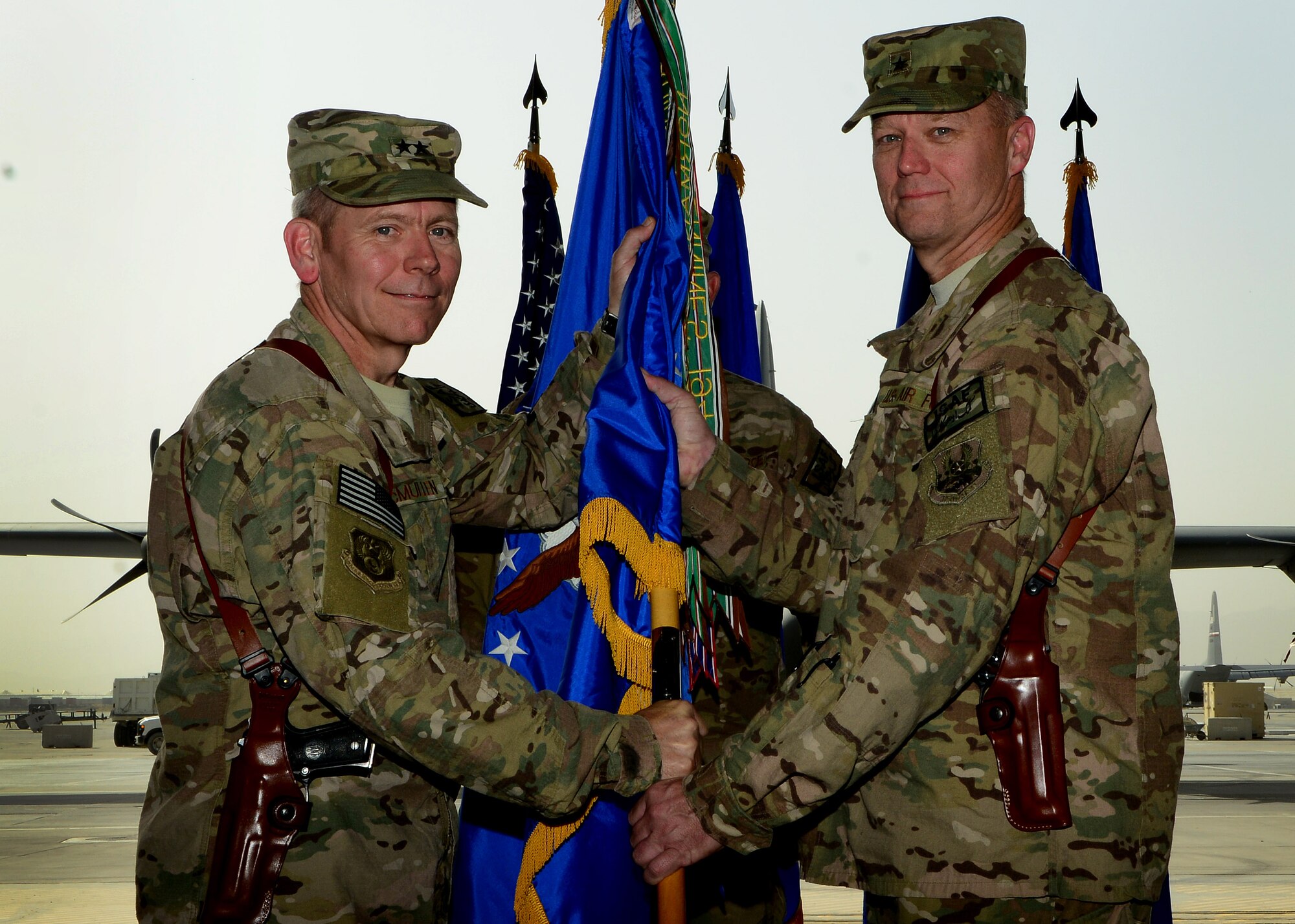 (From left) U.S. Air Force Maj. Gen. John McMullen, 9th Air and Space Expeditionary Task Force Afghanistan commander passes the 455th Air Expeditionary Wing guidon to Brig. Gen. Mark Kelly to assume command during a change of command ceremony at Bagram Airfield, Afghanistan July 3, 2014. Kelly was the commander for the 345th Fighter Wing at Eielson Air Force Base, Alaska.  (U.S. Air Force photo by Staff Sgt. Evelyn Chavez/Released)