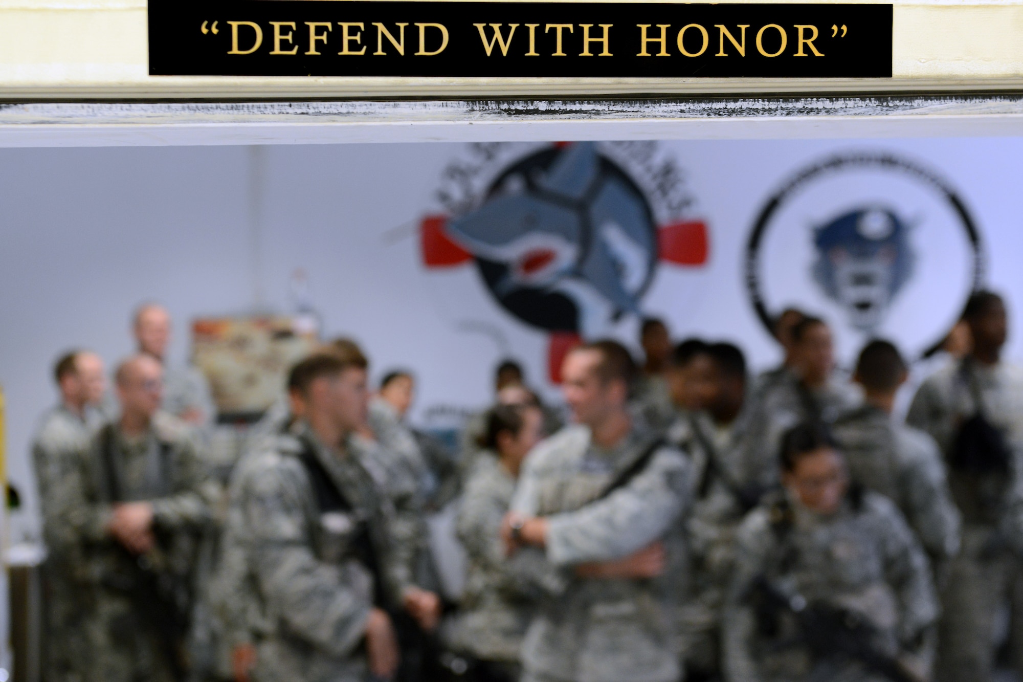 After clearing their weapons, 31st Security Forces Airmen pass through a door marked “defend with honor” and form up for “guard mount,” July 1, 2014, at Aviano Air Base, Italy. Guard mount is a pre-shift formation where critical information is passed to the flight before the start of the shift. (U.S. Air Force photo/Airman 1st Class Ryan Conroy) 