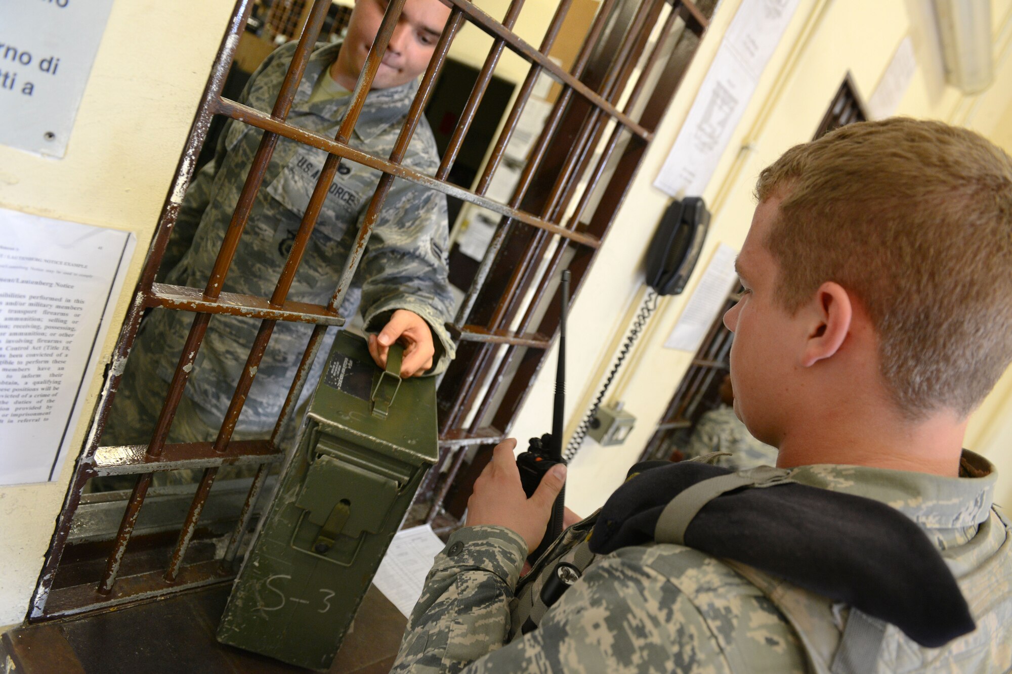 Airman 1st Class Matthew Durante hands Airman 1st Class Colyn Fox a radio and ammunition box, July 1, 2014, at Aviano Air Base, Italy. Armorers arm approximately 50 people before every shift to protect the more than 8,000 who live and work on base. Durante and Fox are both flight armorers. (U.S. Air Force photo/Airman 1st Class Ryan Conroy) 