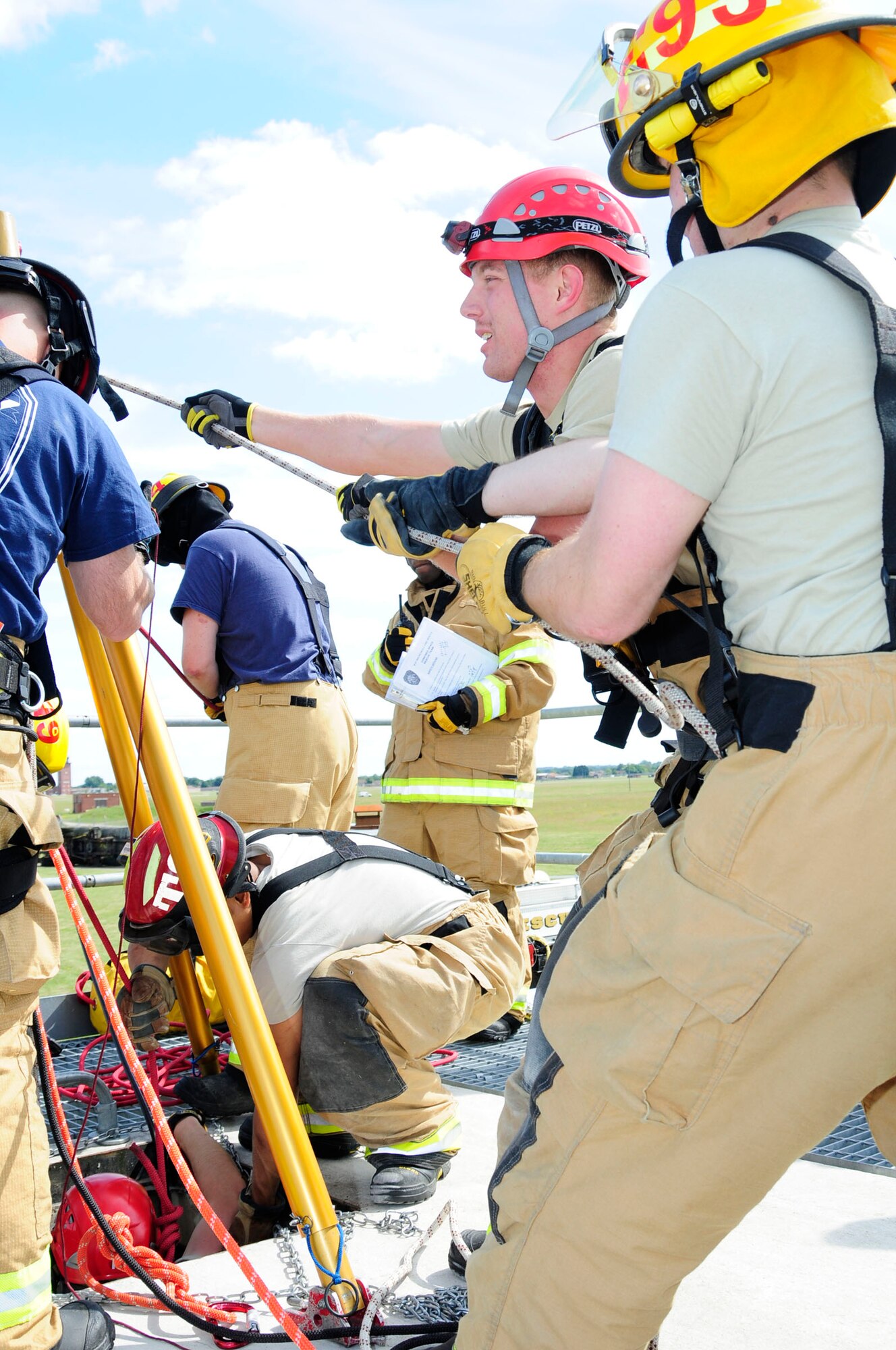 Firefighters from the 100th Civil Engineer Squadron Fire Department raise a responder from a confined space using a mechanical advantage system during confined-space training June 26, 2014, on RAF Mildenhall, England. Firefighters perform a wide variety of training to hone their life-saving skills and ensure they’re prepared for any emergency. (U.S. Air Force photo/Karen Abeyasekere/Released)