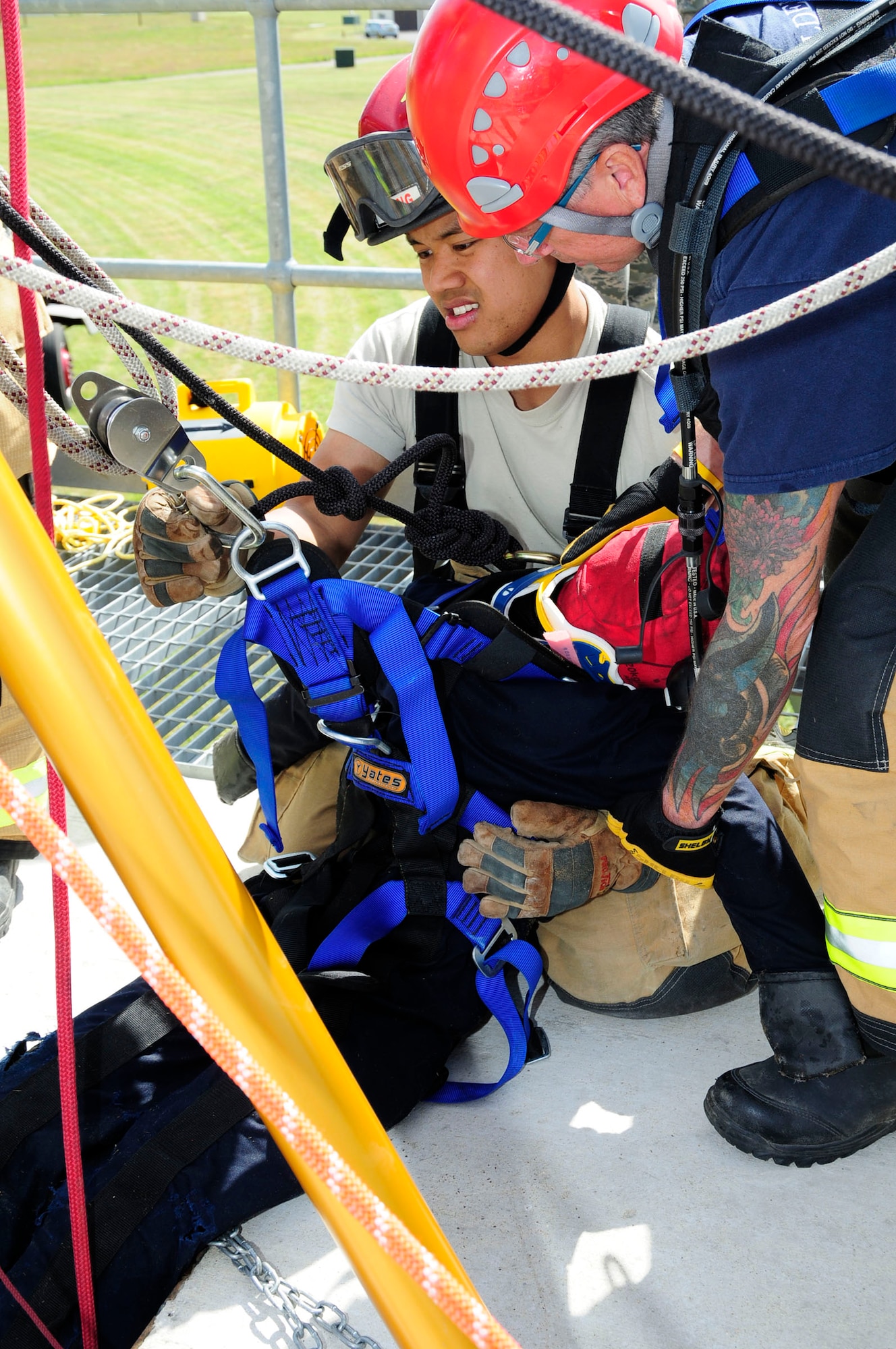 U.S. Air Force Staff Sgt. Anthony Thlang, left, 100th Civil Engineer Squadron Fire Department crew chief from Seattle, and Paul Cusden, 100th CES Fire Department firefighter from Ramsgate, Kent, England, remove a simulated victim from a confined space during training June 26, 2014, on RAF Mildenhall, England. The training was part of a U.S. Air Forces in Europe inspection where a simulated child was trapped inside a pipe and firefighters responded to the scene. (U.S. Air Force photo/Karen Abeyasekere/Released)