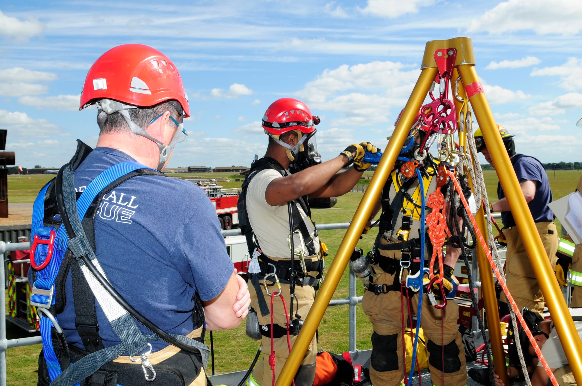 Paul Cusden, left, 100th Civil Engineer Squadron Fire Department firefighter from Ramsgate, Kent, England, and U.S. Air Force Senior Airman Theodore Willis, 100th CES Fire Department firefighter and driver/operator from Stockton, Calif., attach rescue rope lines to a tripod during confined-space training June 26, 2014, at the fire training area on RAF Mildenhall, England. The lines are used for raising and lowering responders and victims. A safety line is also attached to prevent freefall in case of rope system failure. (U.S. Air Force photo/Karen Abeyasekere/Released)