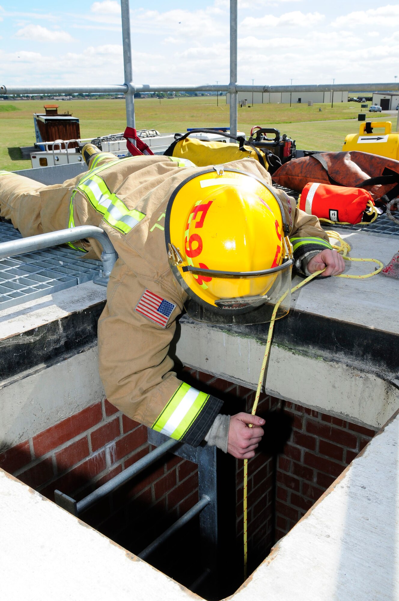 U.S. Air Force Airman Cody Eastridge, 100th CES Fire Department firefighter from Sacremento, Calif., lowers a monitoring device into a confined space to determine whether or not an atmospheric hazard exists June 26, 2014, on RAF Mildenhall, England. The training was part of a U.S. Air Forces in Europe inspection. (U.S. Air Force photo/Karen Abeyasekere/Released)