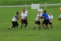 U.S. Air Force Staff Sgt. Juan Duarte, 18th Civil Engineer Squadron firefighter, hands the ball off to his teammate during the flag football game between 18th CES and 18th Secuity Forces Squadron, Kadena Air Base, Japan, July 3, 2014. The football game was part of a day full of competition known as the “Battle of the Badge”. (U.S. Air Force photo by Airman 1st Class Stephen G. Eigel) 
