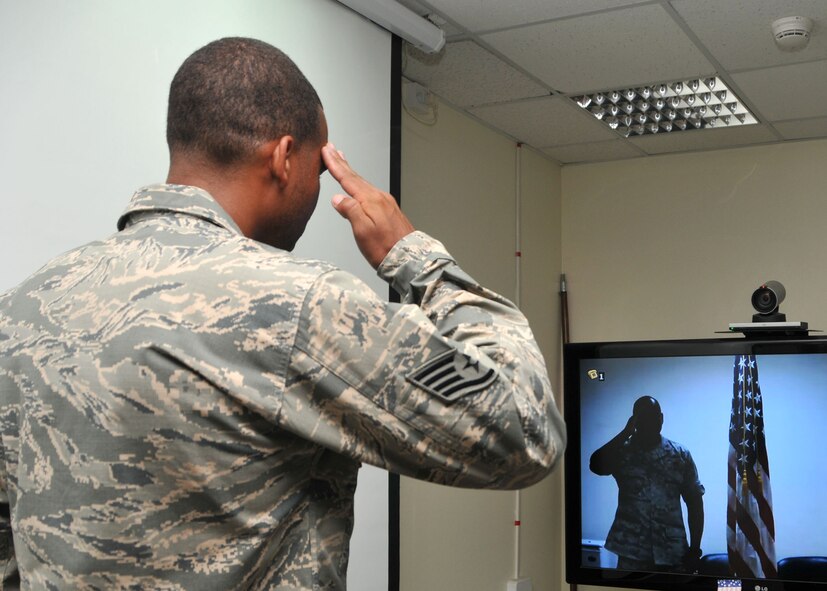 Air Force Staff Sgt. Michael Newsom salutes his father, Air Force Lt. Col. Michael Newsom, at the end of his reenlistment ceremony held at the 380th Air Expeditionary Wing at an undisclosed location in Southwest Asia, June 27, 2014. Lt. Col. Newsom is deployed to a different undisclosed location in Southwest Asia but was able to view the ceremony using video teleconferencing equipment. (U.S. Air Force photo by Senior Master Sgt. Eric Peterson/Released)