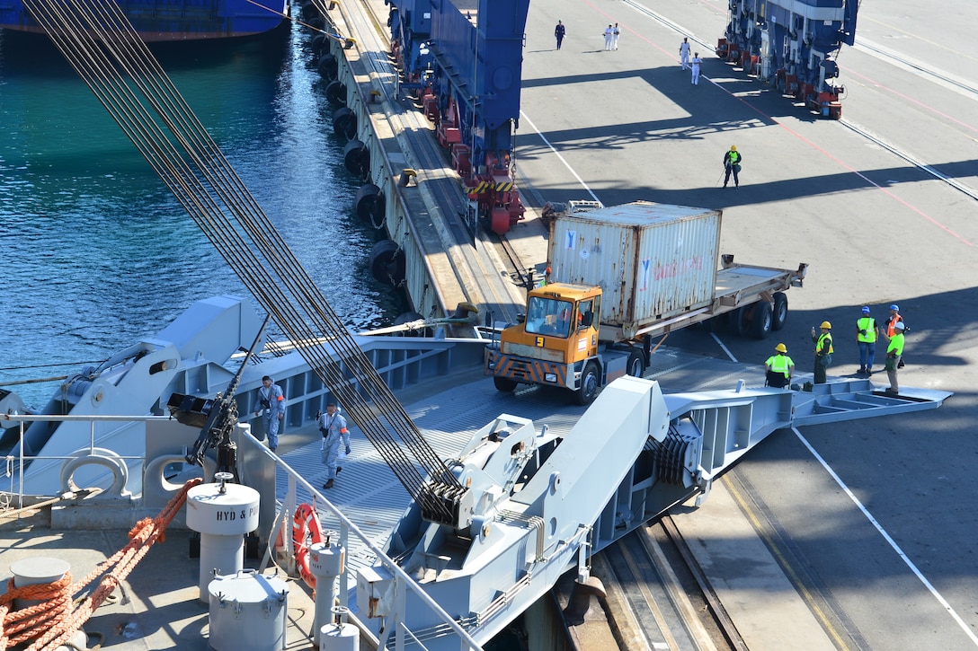 A mafi trailer operator for Medcenter Container Terminal transfers a container from the M/V Ark Futura, a Danish cargo ship, along the dock to the loading deck of M/V Cape Ray, July 2, 2014. The Cape Ray is tasked with the neutralization of specific chemical materials from Syria in accordance with the Organization for the Prohibition of Chemical Weapons guidelines while operating in international waters.