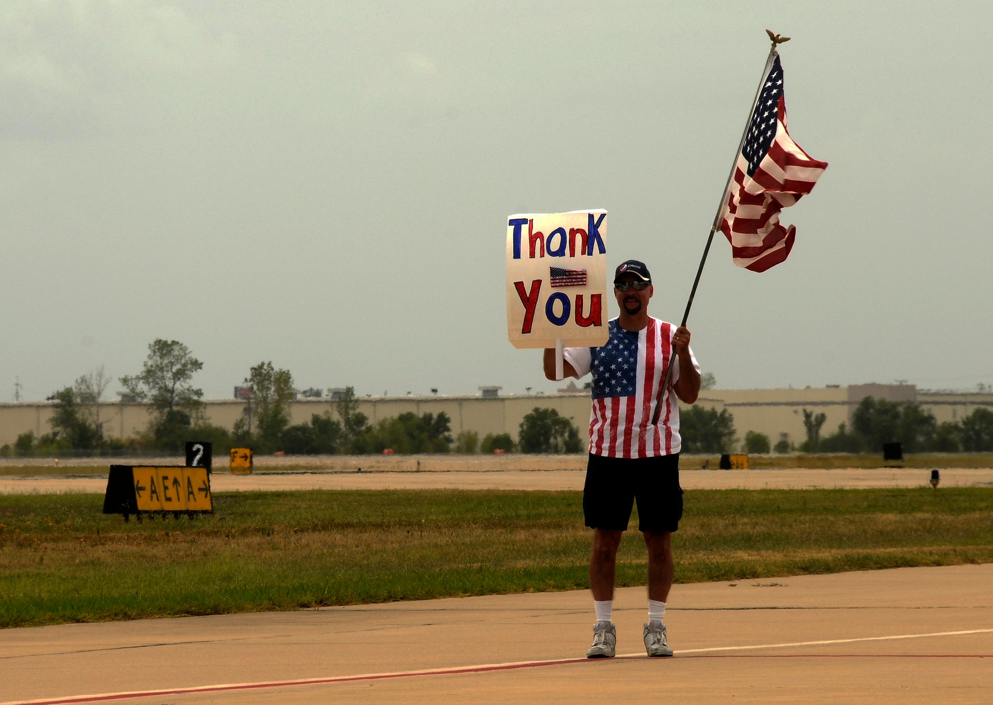 Local military supporter Dave Burns waves an American flag for 188th Wing members following their July 2, 2012 departure for a deployment to Bagram Airfield, Afghanistan in support of Operation Enduring Freedom. Burns often posts near the flightline and waves an American flag to showcase his support. (U.S. Air National Guard photo by Senior Airman Hannah Landeros)

