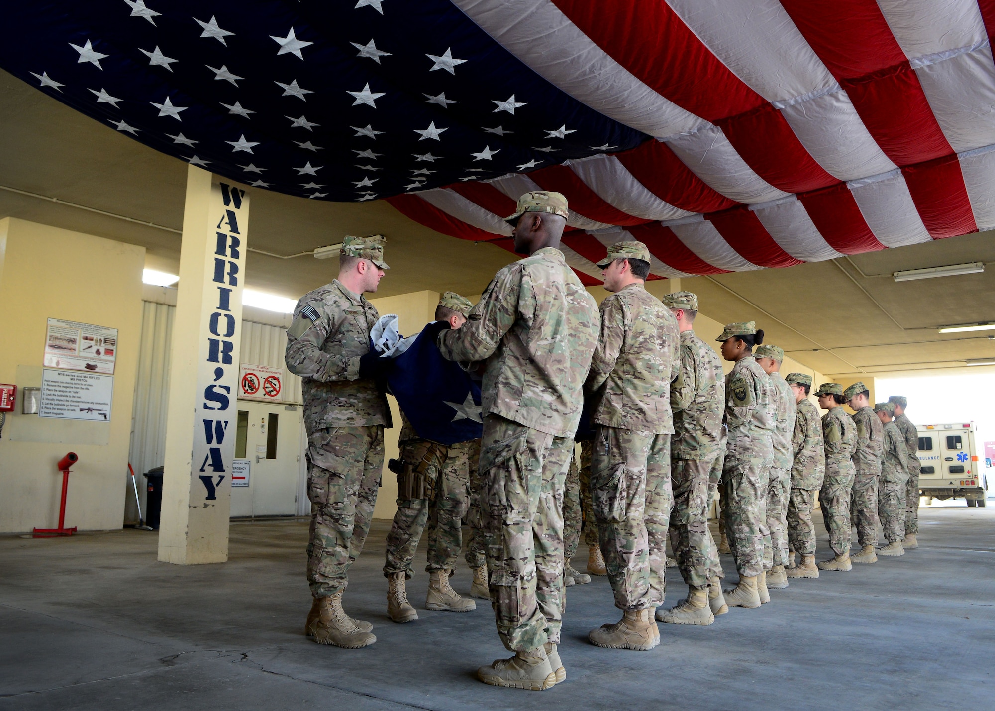 U.S. Air Force Airmen fold an American flag during a folding ceremony at Craig Joint Theater Hospital in Bagram Airfield, Afghanistan July 4, 2014.  A newly dedicated American flag replaced the hospital’s retired flag which was first raised on July 4, 2011.  The new flag hangs on the ceiling of the hospital’s main patient entry also known as “Warriors Way.” (U.S. Air Force photo by Staff Sgt. Evelyn Chavez/Released)