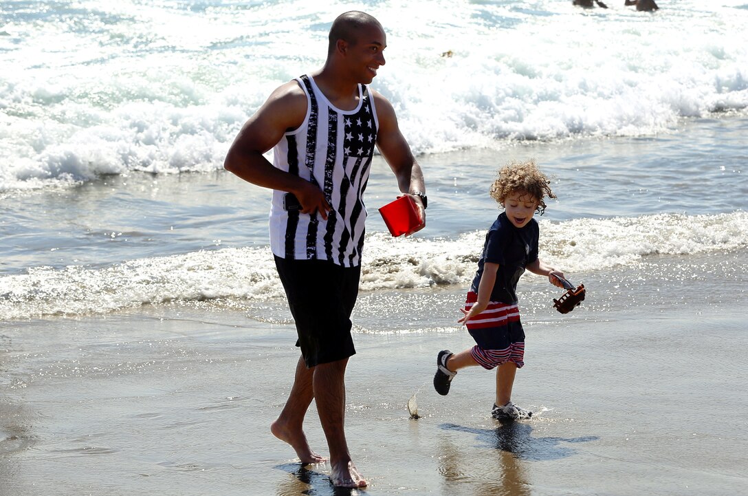 Staff Sgt. Marcus Jenkins and son Aiden, 3,  run out of the water ahead of a wave while at the Beach Bash at Del Mar Beach here July 4.  

The Beach Bash is an on-base event open to service members, dependents and guests and features  live bands, kids’ activities, a tribute to heroes video, a fireworks show and give-aways.
