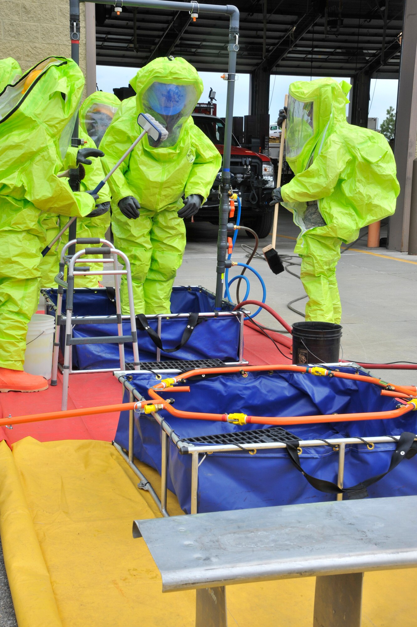 First responders "decontaminate" a fellow Airman during a training exercise at Fairchild Air Force Base, Washington, June 26, 2014. Firefighters from across the Air Force came to Fairchild to attend a hazardous materials technical training course designed to improve weapons of mass destruction and HazMat incident response capability for Fairchild and the surrounding community. Two instructors from the Louis F. Garland Fire Academy traveled to Fairchild to teach the 64-hour course, saving the Air Force money by preventing the need to send 20 students each course to Goodfellow AFB, Texas. (U.S. Air Force photo by Senior Airman Mary O'Dell/Released)