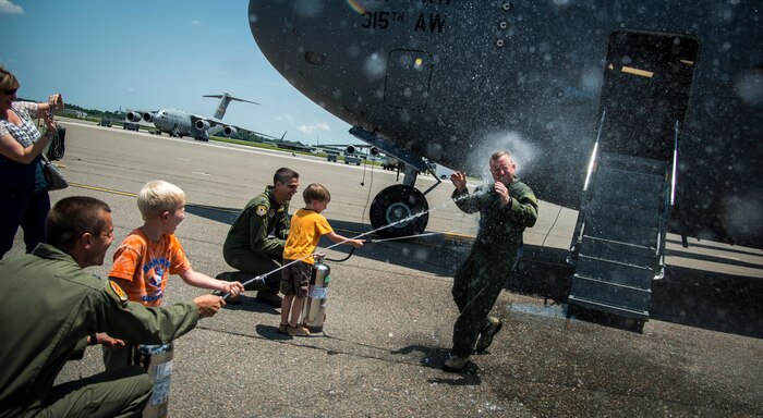 Col. Tony Schenk, 437th Operations Group deputy commander, is sprayed by friends and family July 1, 2014, on the flightline at Joint Base Charleston, S.C. Shenk just completed his ‘fini’ flight, an aviation tradition in which aircrew members are met by their unit comrades, family and friends and soaked with water after completing their final flight with that unit.  (U.S. Air Force photo/ Airman 1st Class Clayton Cupit)