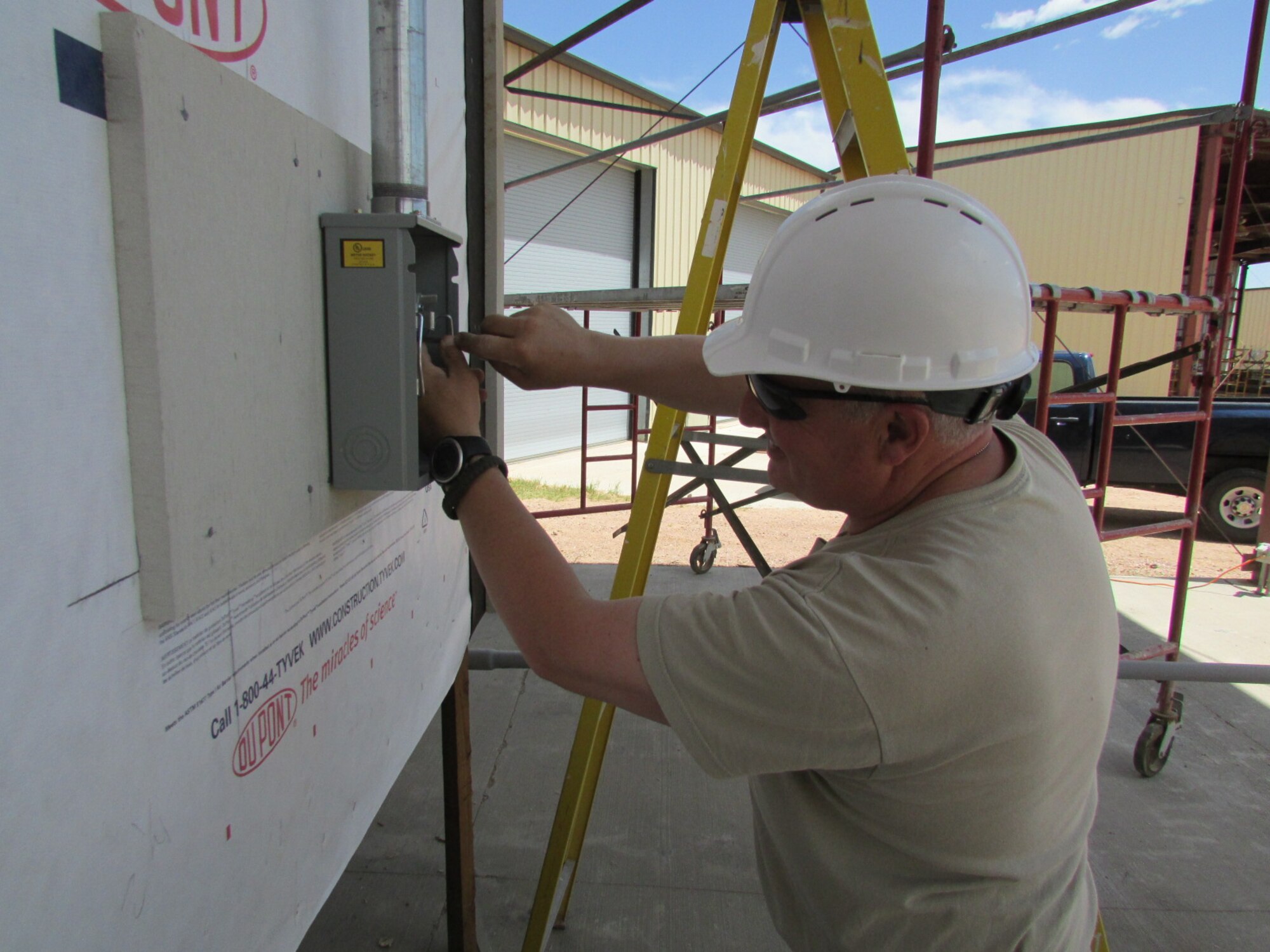Tech Sgt. Garnet Wood, 914 Civil Engineer Squadron, electrician, installs an electrical component  on a Hogan Home at the Field Engineering & Readiness Laboratory site located at the Air Force Academy, Colorado Springs, Colorado on June 9, 2014. A Hogan Home is a traditional Navajo Indian home and, once the homes are completed, declared surplus property and ownership is turned over to the Navajo people. (U.S. Air Force photo by Senior Master Sgt. Michael Haag)