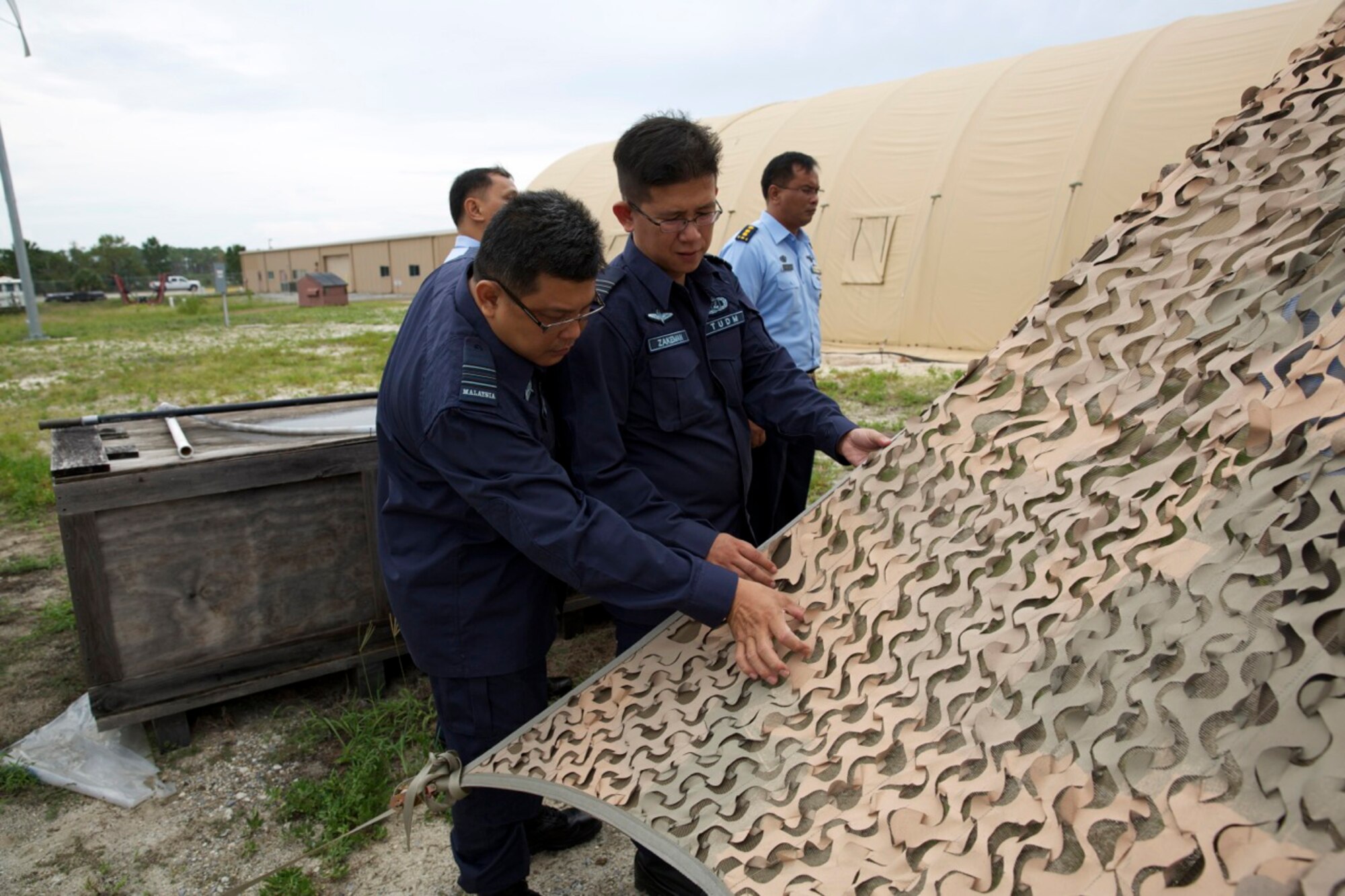 From left, Maj. Mohamed Nizam and Maj. Bin Zakeman of the Royal Malaysian Air Force examine an external layer of an advanced energy-efficient shelter system at the Requirements and Acquisition Division of the Air Force Civil Engineer Center’s Readiness Directorate at Tyndall Air Force Base, Fla., June 23, 2014. The foreign officers’ visit was part of the Pacific Unity Subject Matter Expert Exchange, a program sponsored by Pacific Air Forces designed to strengthen cooperation with select Pacific nations. During their tour, the visitors had the opportunity to see several projects being developed and tested by AFCEC including this example of a shelter systems designed to significantly reduce power consumption on expeditionary bases. (U.S. Air Force photo/Eddie Green/Released)