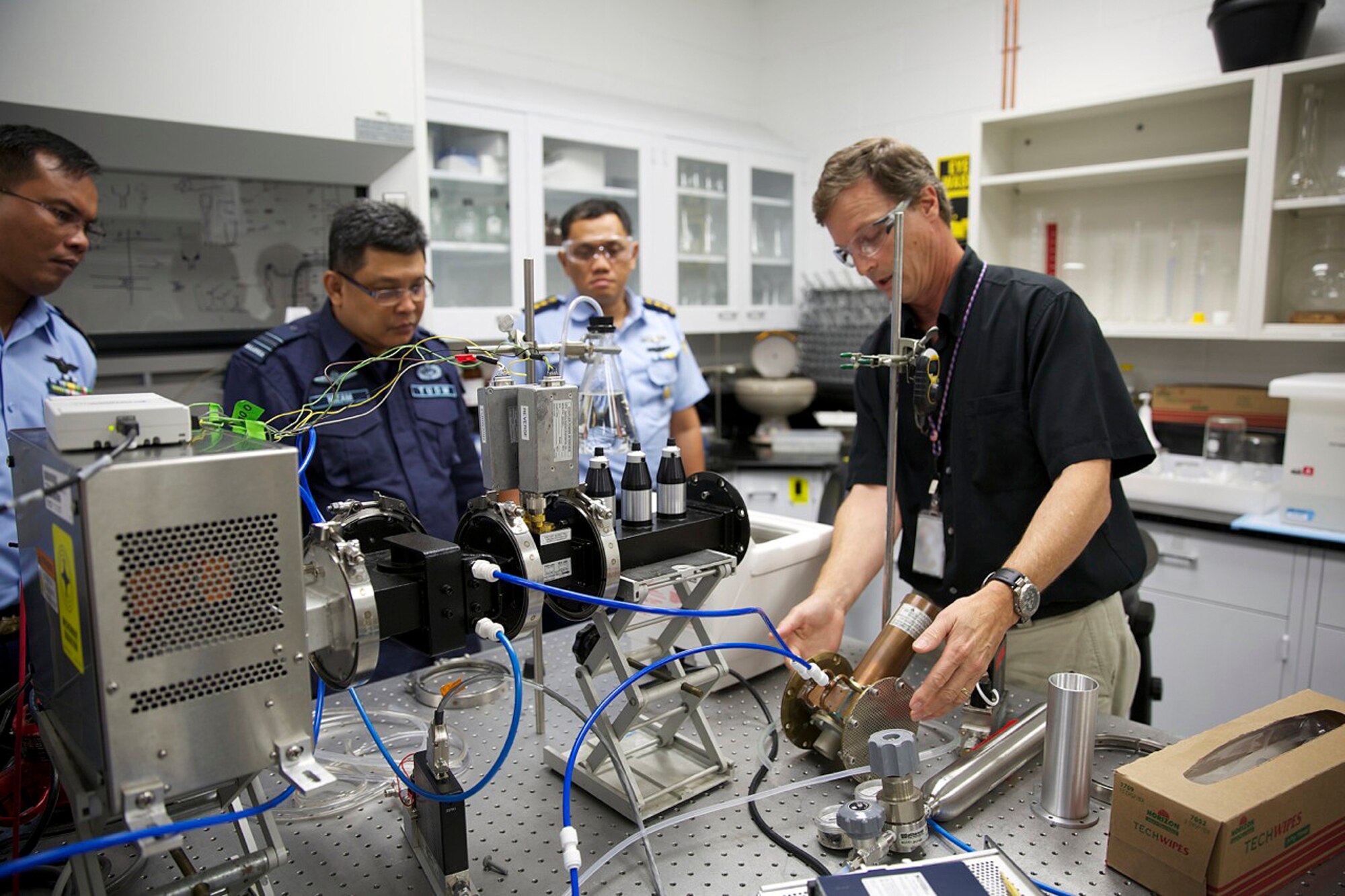 At left, Michael Henley, physical scientist with AFCEC's Readiness Directorate Requirements and Acquisition Division at Tyndall Air Force Base, Fla., explains the process of using microwave emitters to accelerate chemical reactions to officers from the Indonesian and Royal Malaysian Air Forces, June 23, 2014. The visiting officers toured AFCEC’s materials laboratory as part of the Pacific Unity Subject Matter Expert Exchange. Pacific Unity is a program sponsored by Pacific Air Forces designed to strengthen cooperation with select Pacific nations through humanitarian assistance, disaster response preparedness, civil military operations and idea exchanges. (U.S. Air Force photo/Eddie Green/Released)