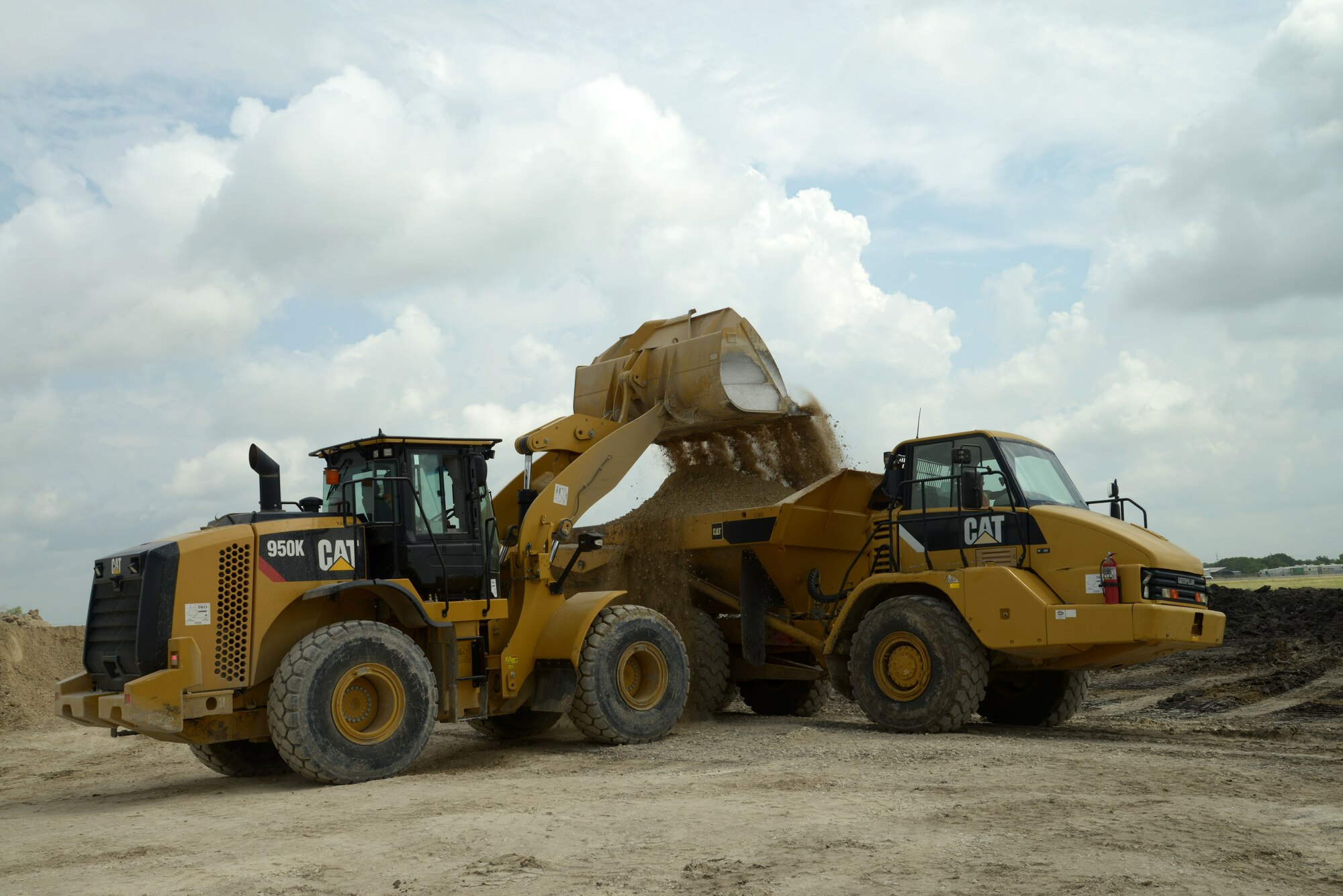 Senior Airman Zachery Webbkeel and Airman 1st Class Jeff Njenga, 820th Rapid Engineer Deployable Heavy Operational Repair Squadron Engineer heavy equipment operators, load and haul pavement to be placed on the runway June 23 at Joint Base San Antonio-Randolph's Seguin Auxiliary Airfield. (U.S. Air Force photo by Joel Martinez)