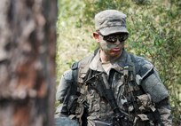 An Army Ranger student watches as Soldiers discuss strategy before an upcoming maneuver in the woods of the Eglin Air Force Base, Fla., range.  Students complete the final phase of the Army Ranger course with the 6th Ranger Training Battalion.  Instructors expose the students to an 18-day field training that includes airborne and helicopter assaults, small boat operations, river and swamp crossings.  (U.S. Air Force photo/Tech. Sgt. Samuel King Jr.)