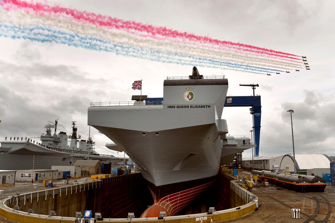 The British flight demonstration team, the Red Arrows, conduct a fly over of the HMS Queen Elizabeth during a ship naming ceremony in Rosyth, Scotland, July 4, 2014.