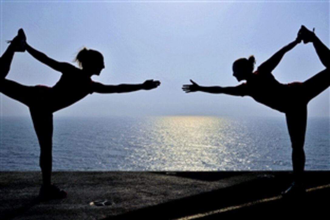 U.S. Navy Lt. Diane Kruse, left, and Lt. Alyse Dason practice yoga poses on the flight deck of the aircraft carrier USS George H.W. Bush in the Arabian Gulf, July 5, 2014. The ship is supporting maritime security operations and theater security cooperation efforts in the U.S. 5th Fleet area of responsibility