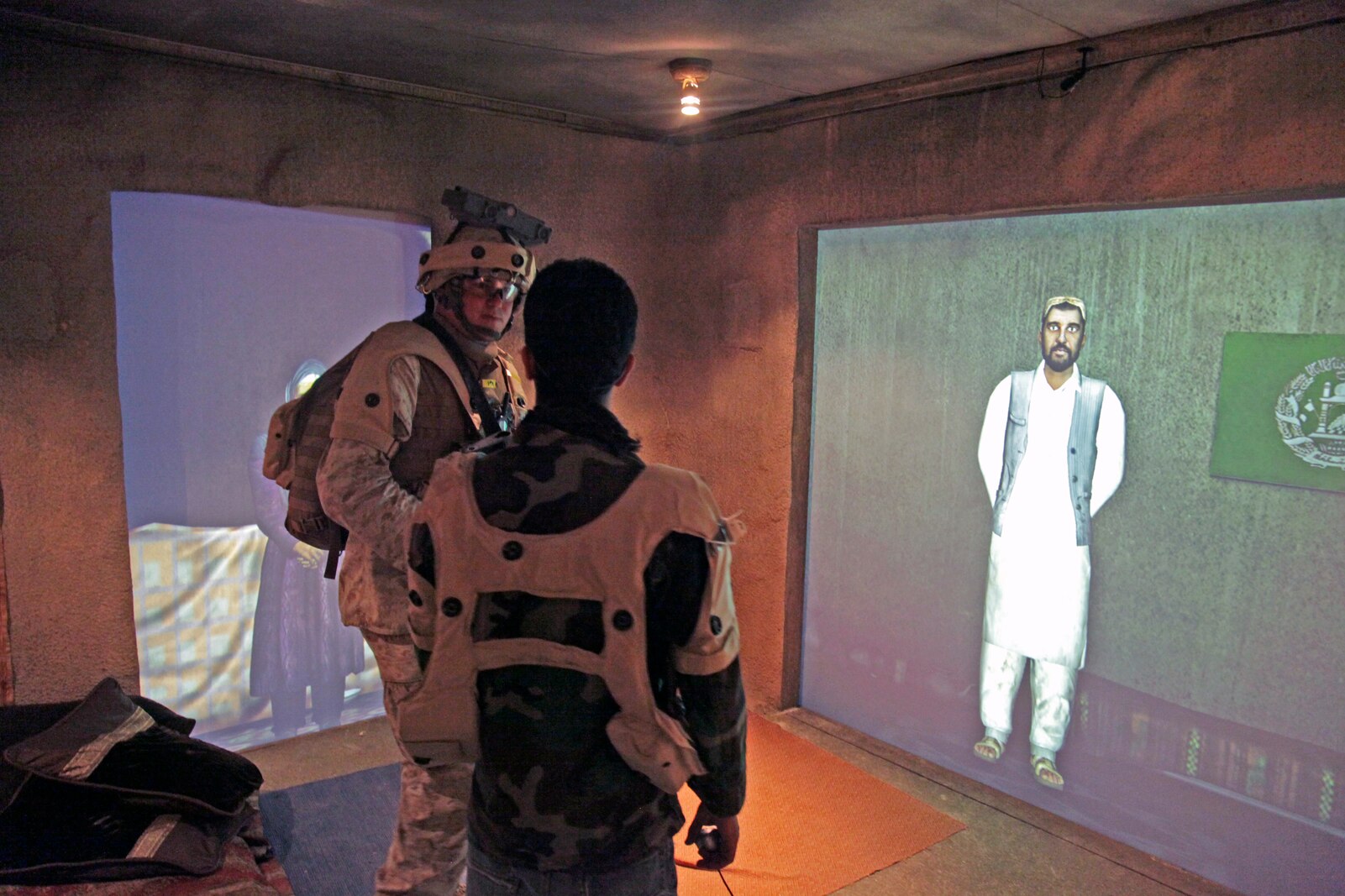 U.S. Marine Cpl. Rian Martinez with Charlie Company, 1st Battalion, 5th Marine Regiment (1/5) meets with an Afghani role player and a projected role player in the Infantry Immersion Trainer aboard Camp Pendleton Calif. Sept. 15, 2010. The training facility is using new technology for training such as motion capture role players. (U.S. Marine Corps photo by Lance Cpl. Nathan McCord / Released)