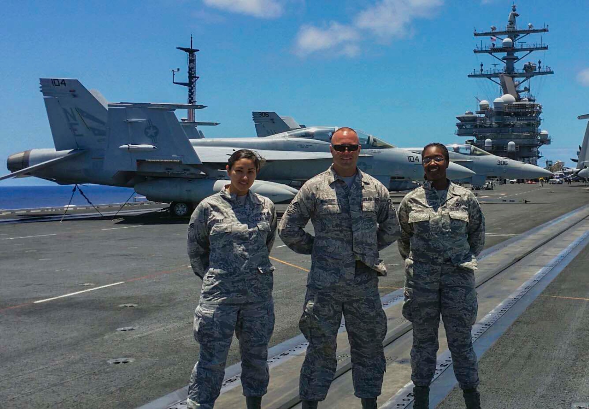 From left: Senior Airman Kathy Sells, 15th Operations Support Squadron Airfield Management Operations Team, Tech. Sgt. Bryan Masters, Airfield Management Operations NCO in charge, and Senior Airman Trenecia Carroll, 15th OSS Airfield Management Operations Team, pose in front Navy F-18 Hornets after landing on the USS Reagan (CVN 76) June 25, 2014. The team was onboard the ship to train Sailors on the rules of driving on the airfield at Joint Base pearl Harbor-Hickam ahead of their arrival here for the Rim of the Pacific 2014 exercise. RIMPAC is a U.S. Pacific Command-hosted biennial multinational maritime exercise designed to foster and sustain international cooperation on the security of the world's oceans. (Courtesy photo)
