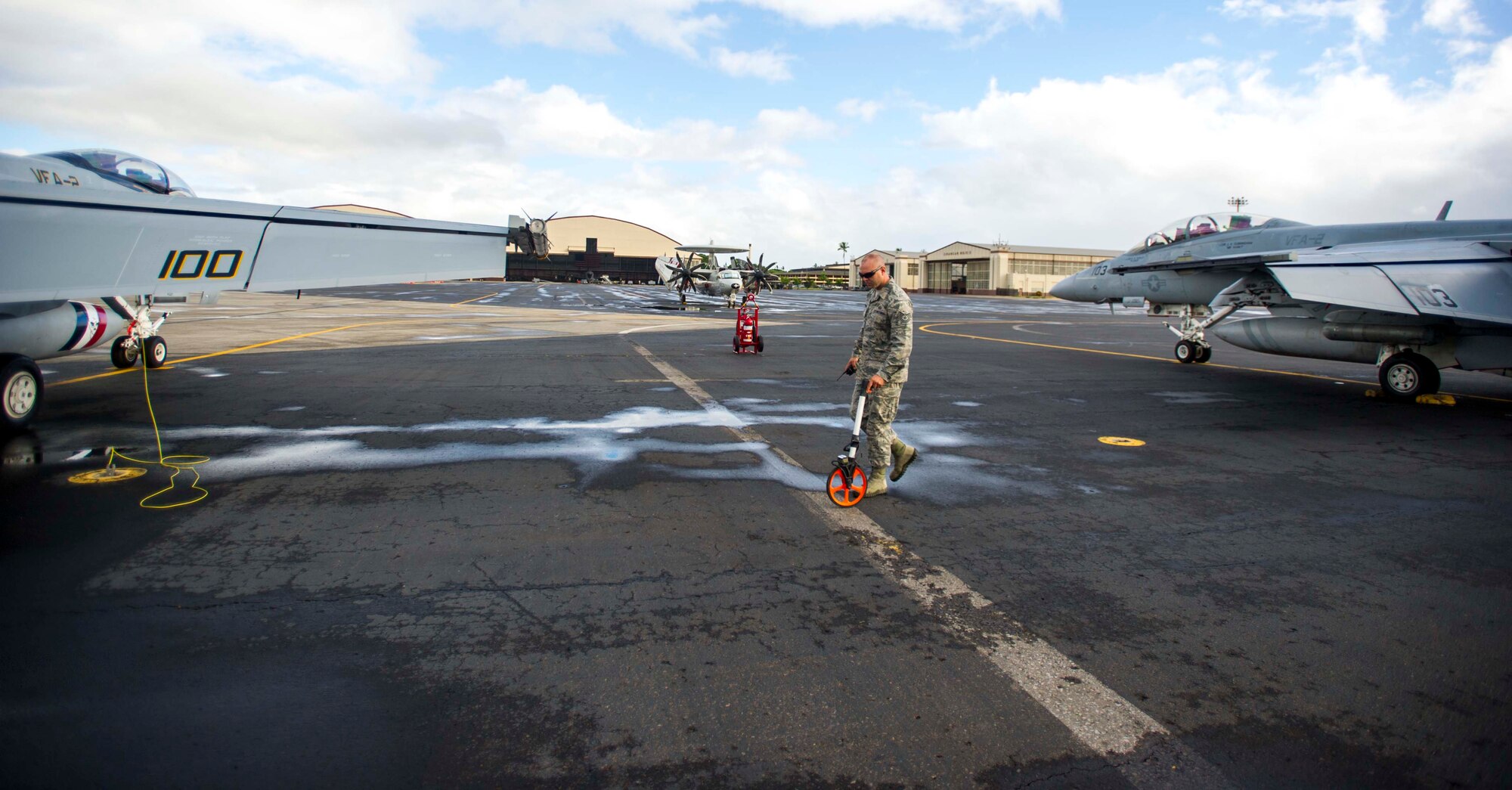 Tech. Sgt. Bryan Masters, 15th Operations Support Squadron Airfield Management Operations NCO in charge, uses a measuring wheel to measure the distance between two Navy F-18 Hornets parked on the flightline at Joint Base Pearl Harbor-Hickam, Hawaii, July 3, 2014. The measuring wheel is used to ensure all aircraft parked on the flightline here have the required amount of space. The F-18s are here participating in the Rim of the Pacific 2014 exercise. RIMPAC is a U.S. Pacific Command-hosted biennial multinational maritime exercise designed to foster and sustain international cooperation on the security of the world's oceans. (U.S. Air Force photo by Tech. Sgt. Terri Paden)