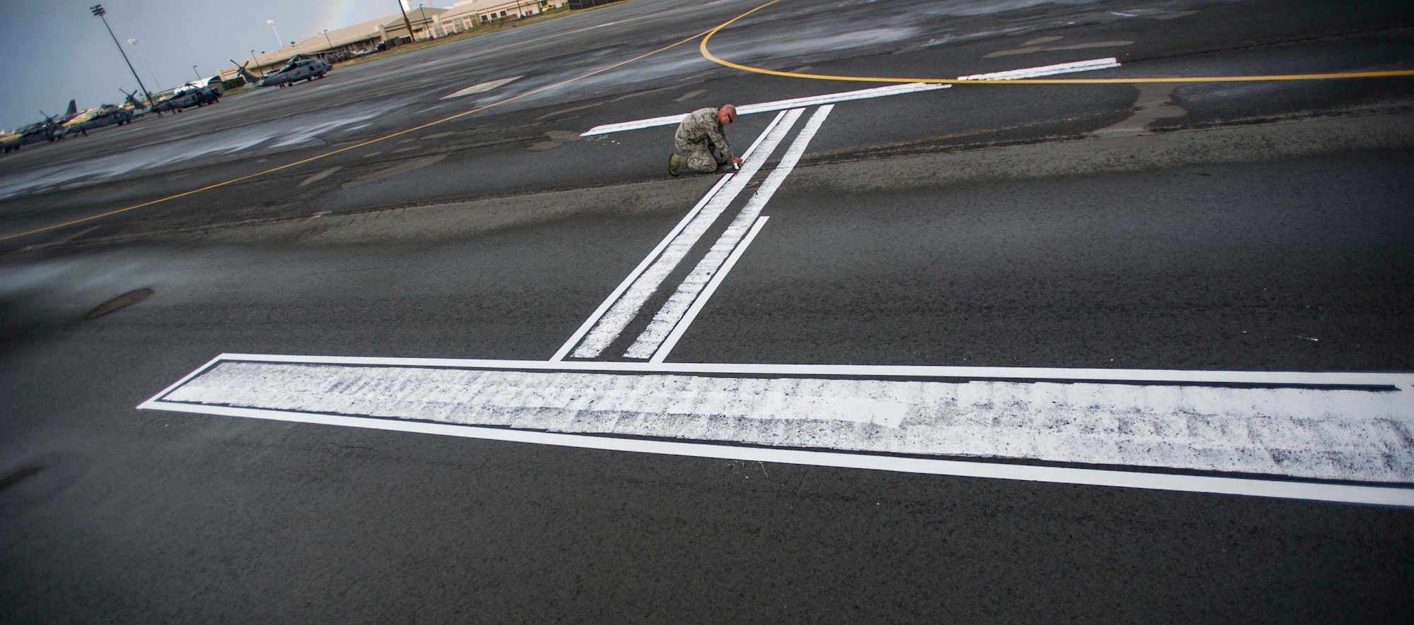 Tech. Sgt. Bryan Masters, 15th Operations Support Squadron Airfield Management Operations NCO in charge, applies reflective tape to the temporary helipad on the flightline at Joint Base Pearl Harbor-Hickam, Hawaii, July 3, 2014. The helipad was constructed by the airfield operations management team to ensure more efficient helicopter operations during the Rim of the Pacific 2014 exercise. RIMPAC is a U.S. Pacific Command-hosted biennial multinational maritime exercise designed to foster and sustain international cooperation on the security of the world's oceans. (U.S. Air Force photo by Tech. Sgt. Terri Paden)