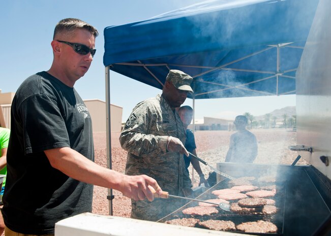 Tech. Sgt. Sean Smyth (left), 820th RED HORSE pavements and equipment operator, and Master Sgt. Anthony Smith, 99th Civil Engineer Squadron first sergeant, grill burgers during Freedom Fest at the Warrior Fitness Center, July 3, 2014, at Nellis Air Force Base, Nev. The Freedom Fest, hosted by the 99th Force Support Squadron, was a chance for Airmen and their families to come together and celebrate Independence Day. (U.S. Air Force photo by Airman 1st Class Thomas Spangler)
