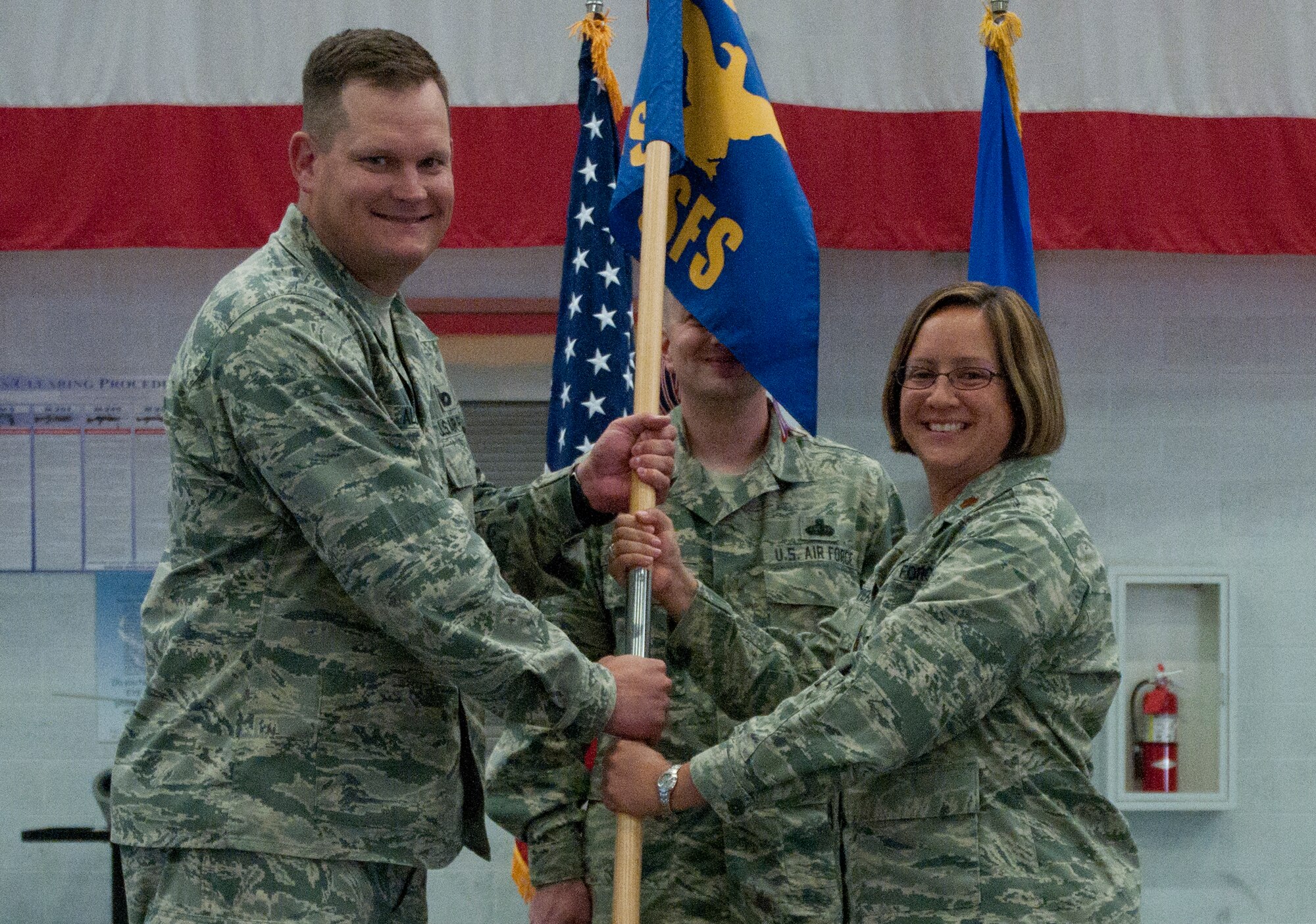 Col. Craig Alton, 90th Security Forces Group commander, passes the 90th Security Forces Squadron guidon to Maj. Amy Rivera as she assumes command of the squadron during a change-of-command ceremony in the Peace Keeper High Bay on F.E. Warren Air Force Base, Wyo., July 1, 2014. (U.S. Air Force photo by Airman Malcolm Mayfield)