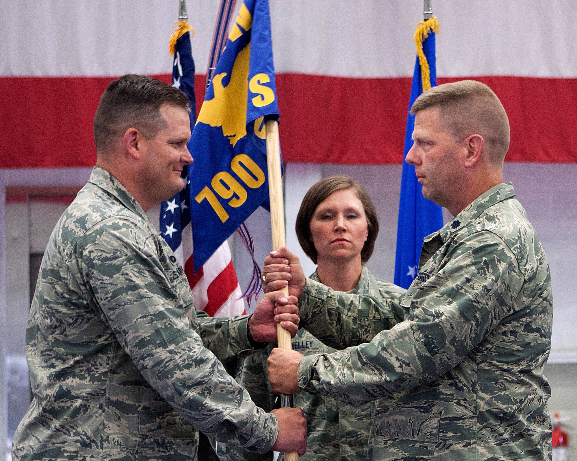 Col. Craig Allton, 90th Security Forces Group commander, passes the 790th Missile Security Forces Squadron guidon to Lt. Col. Christopher Johnson as he assumes command of the squadron during a change-of-command ceremony on F.E. Warren Air Force Base, Wyo., July 2, 2014. Master Sgt. Rebecca McNelley, 790th MSFS first sergeant, stands by to take the guidon back from Johnson. (U.S. Air Force photo by R.J. Oriez)