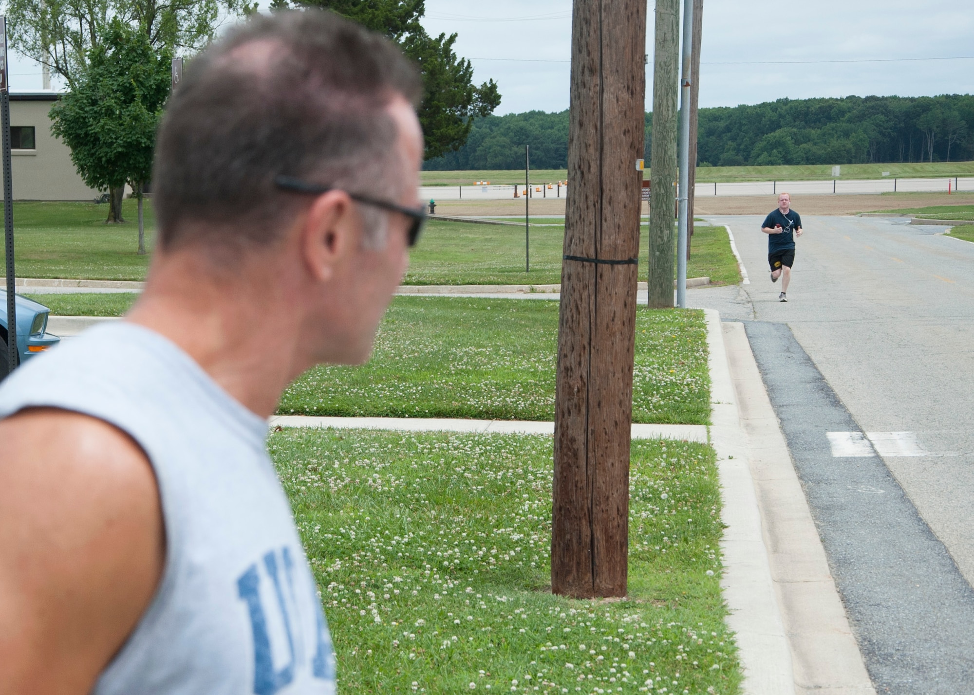 John Walters, 436th Aerospace Medicine Squadron fitness program managers, watches Senior Airman Ben Fugler, 436th Maintenance Squadron C-5M Super Galaxy crew chief, push hard while running a 5K June 27, 2014, on Dover Air Force Base, Del. Fugler credits the program with helping him score over a 90 on all of his physical training tests. (U.S. Air Force photo/Senior Airman Jared Duhon) 