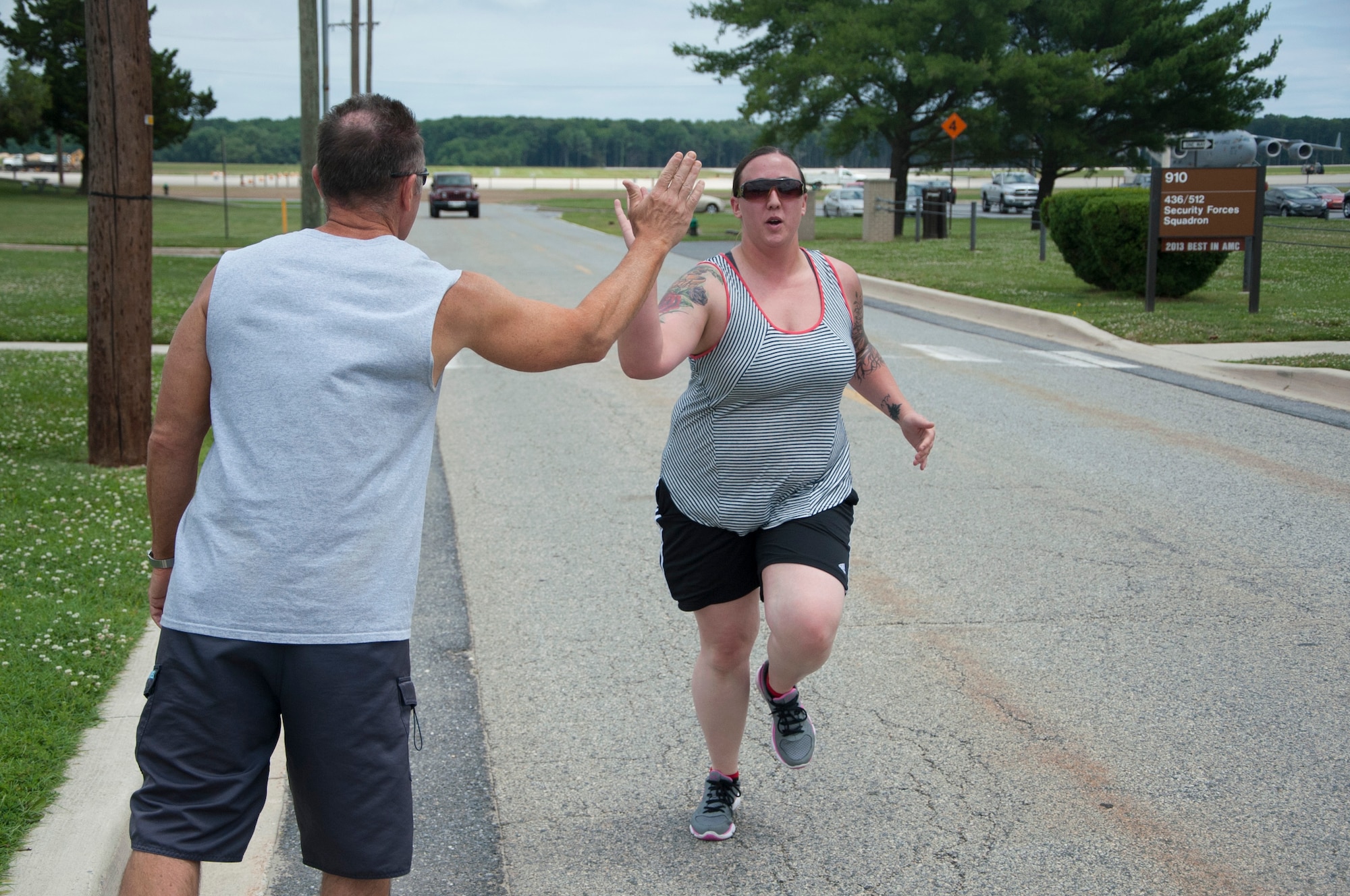 Airman 1st Class Kendra Valitchka, 736th Aircraft Maintenance Squadron C-17 Globemaster III crew chief, high-fives John Walters, 436th Aerospace Medicine Squadron fitness program manager, after running a 5K June 27, 2014, on Dover Air Force Base, Del. Since starting the 90 in 90” program in January, Valitchka has dropped 2 minutes off her 1.5 mile runtime. (U.S. Air Force photo/Senior Airman Jared Duhon)