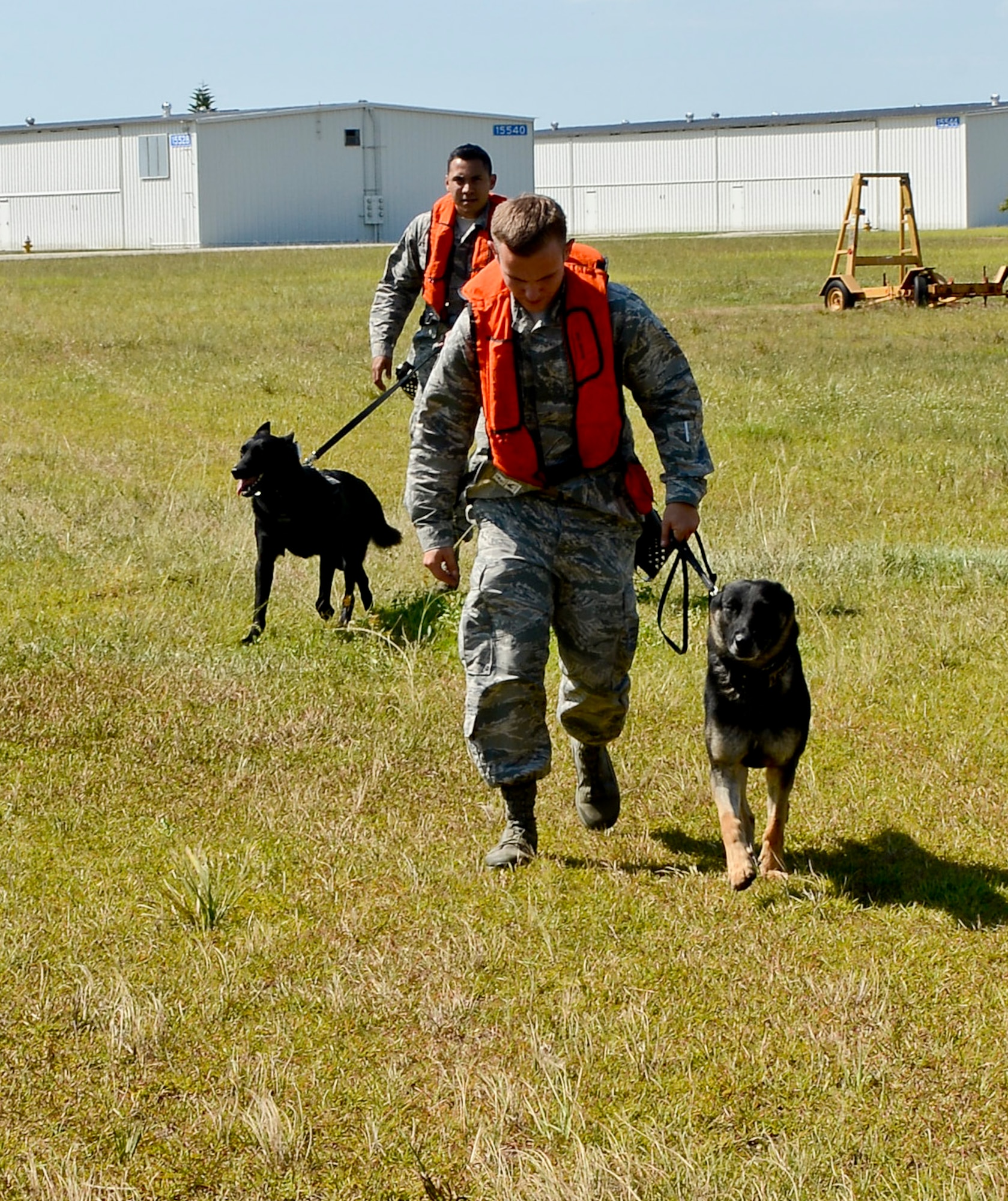 Senior Airman Tyler Sexton, 6th Security Forces Squadron military working dog handler, MWD Alex, Staff Sgt. Alex Lazala, 6th SFS MWD handler, and MWD Jimmy advance toward the Sikorsky MH-60T Jayhawk during a training session with the U.S. Coast Guard Air Station in Clearwater, Fla., June 30, 2014. This training allowed the handlers to evaluate their four-legged partners’ reactions when exposed to the loud noise and high altitude. (U.S. Air Force photo by Senior Airman Melanie Bulow-Gonterman/Released)