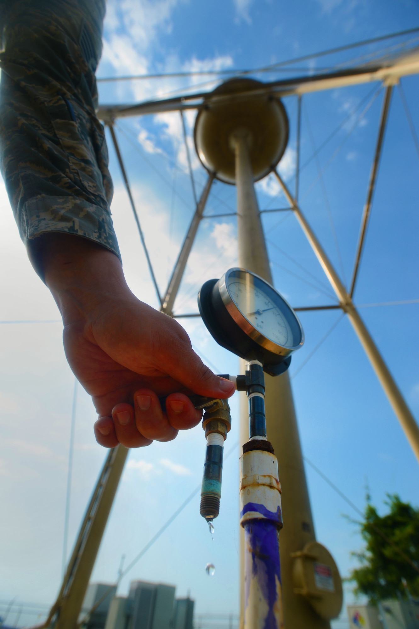 A 20th Civil Engineer Squadron water and fuels systems maintenance Airman inspects a water pressure gauge at Shaw Air Force Base, S.C., July 8, 2014. A valve attached to the gauge can release water pressure inside of the water tower to ensure it maintains proper pounds per square inch. (U.S. Air Force photo by Airman 1st Class Jensen Stidham/Released)