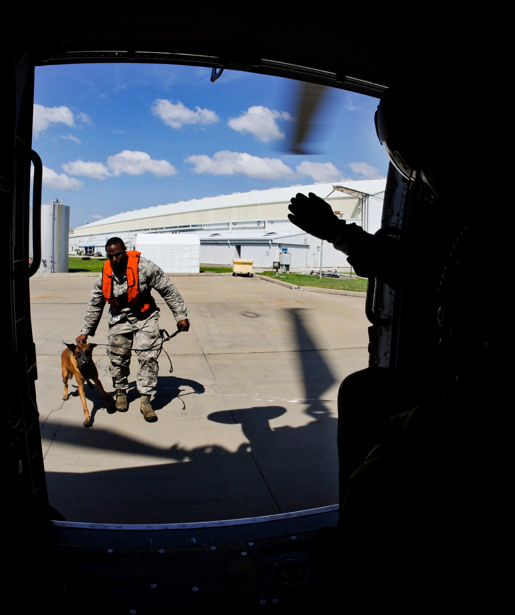 Staff Sgt. Winston Campbell, 6th Security Forces Squadron military working dog handler, and MWD Lleonard advance toward the Sikorsky MH-60T Jayhawk during a training session with the U.S. Coast Guard Air Station in Clearwater, Fla., June 30, 2014. Exposing a dog to the noise and high altitude uses successive approximation to acclimate the dog, which is crucial when deployed.  (U.S. Air Force photo by Senior Airman Melanie Bulow-Gonterman/Released) 