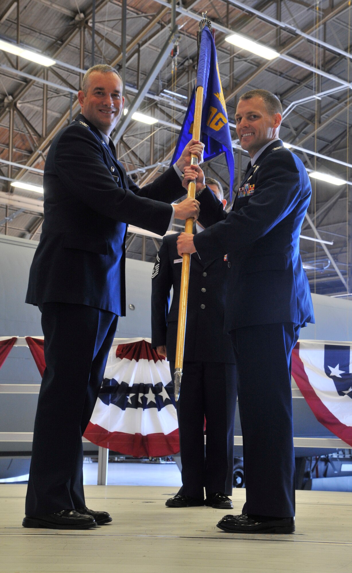 Col. Brian Newberry passes the guidon to Col. Scott Gundlach during a change of command ceremony at Fairchild Air Force Base, Washington, July 8, 2014. Gundlach took command of the 92nd Operations Group and previously served as the executive assistant to the commander, U.S. Transportation Command at Scott AFB, Illinois. Newberry is the 92nd Air Refueling Wing commander. (U.S. Air Force photo by Senior Airman Mary O'Dell/Released)