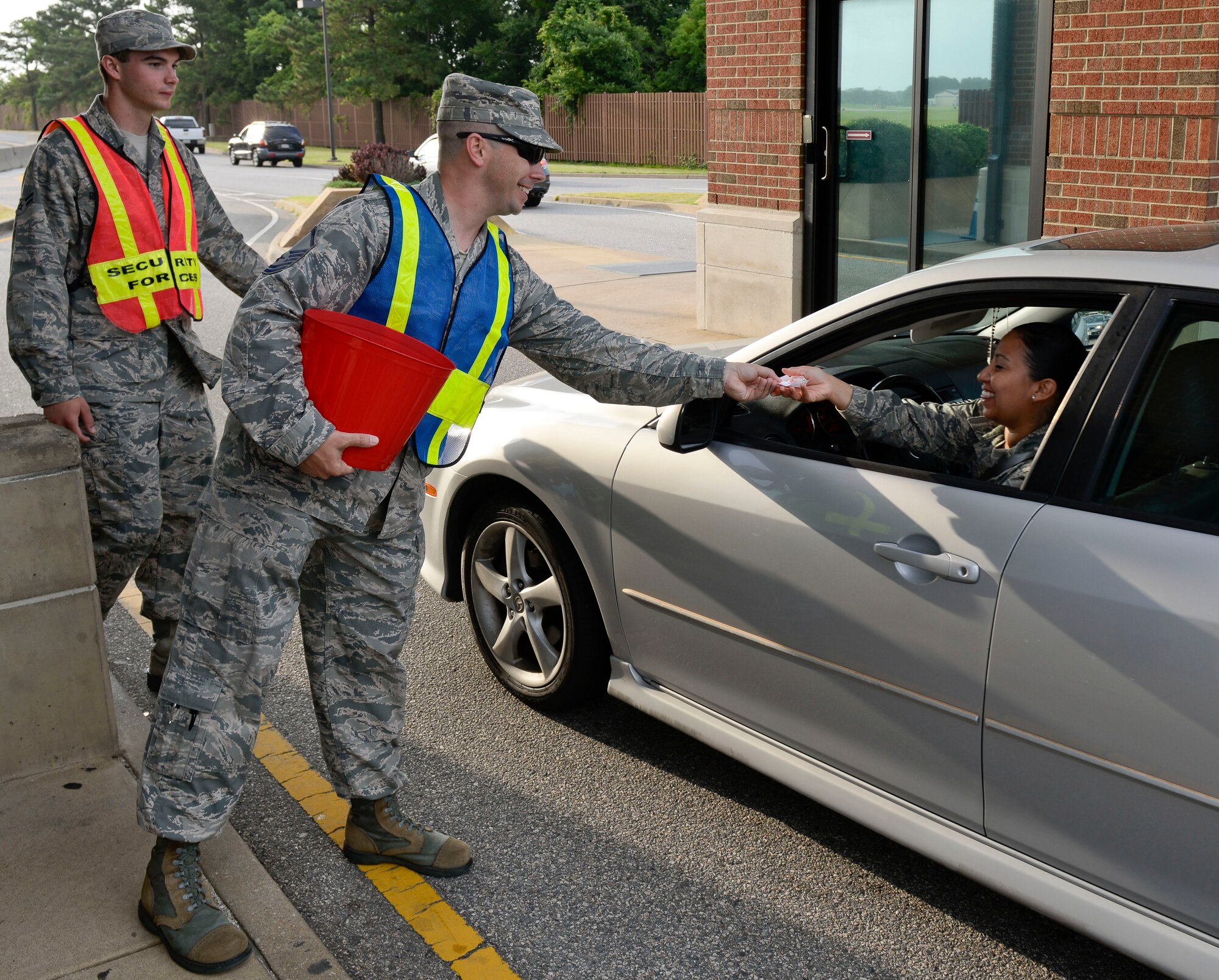 U.S. Air Force Master Sgt. Brian Potvin, Headquarters Air Combat Command Top Three vice president, hands out candy to inbound motorists at the Armistead Gate at Langley Air Force Base, Va., July 3, 2014. The HQ ACC Top Three group handed out more than 2,000 pieces of candy with attached paper wishing people a safe and happy Fourth of July weekend, and a phone number to reach the "Soldiers and Airmen Against Drunk Driving" group. (U.S. Air Force photo by Senior Airman Connor Estes/Released)