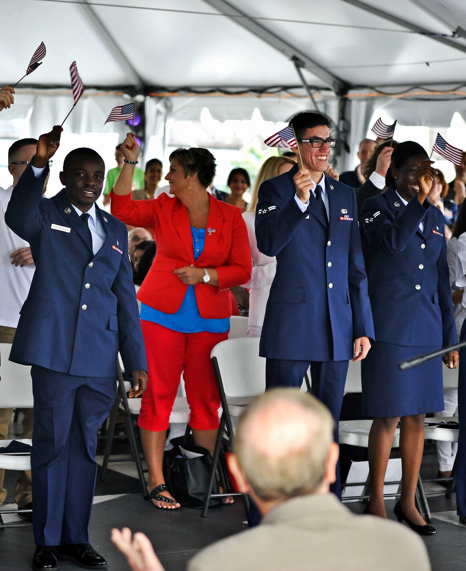 Airmen 1st Class Bonelnelson Rosset Bouangalolo, Eric Re Guerrera and Belinda Wilson wave American flags after a naturalization ceremony July 4, 2014, aboard the USS New Jersey in Camden, N.J. The Airmen are stationed at Joint Base McGuire-Dix-Lakehurst and were three of 35 nominees who became official U.S. citizens on Independence Day. (U.S. Air Force photo by Staff Sgt. Scott Saldukas/Released)