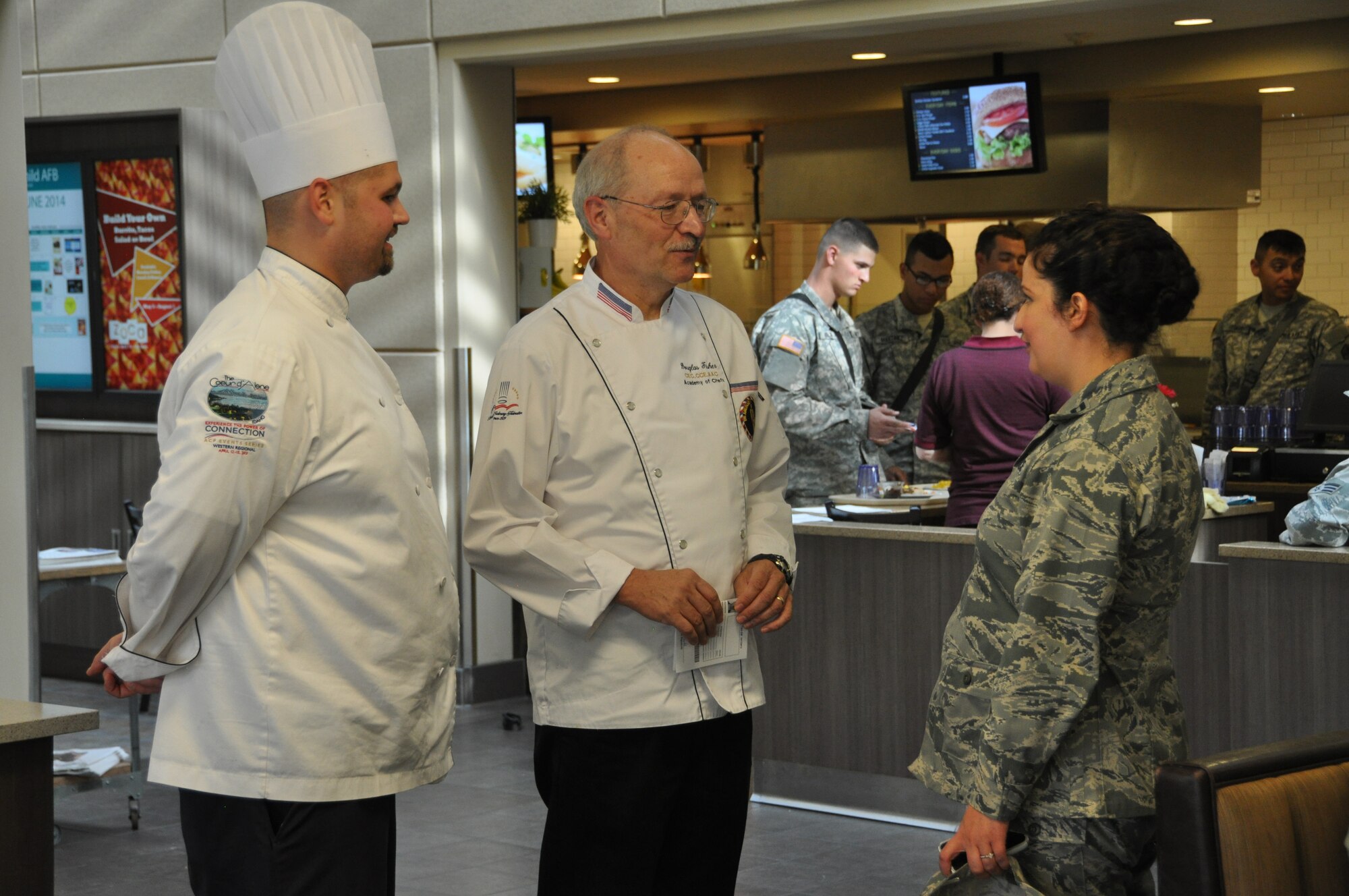 Doug Fisher discusses the cooking competition event with Capt. Pamela Nuila of the 92nd Force Support Squadron at Fairchild Air Force Base, Washington, June 25, 2014. Fisher was the civilian authority on hand as one of the judges for the competition. (U.S. Air Force photo by Staff Sgt. Robert Conniff/Released)