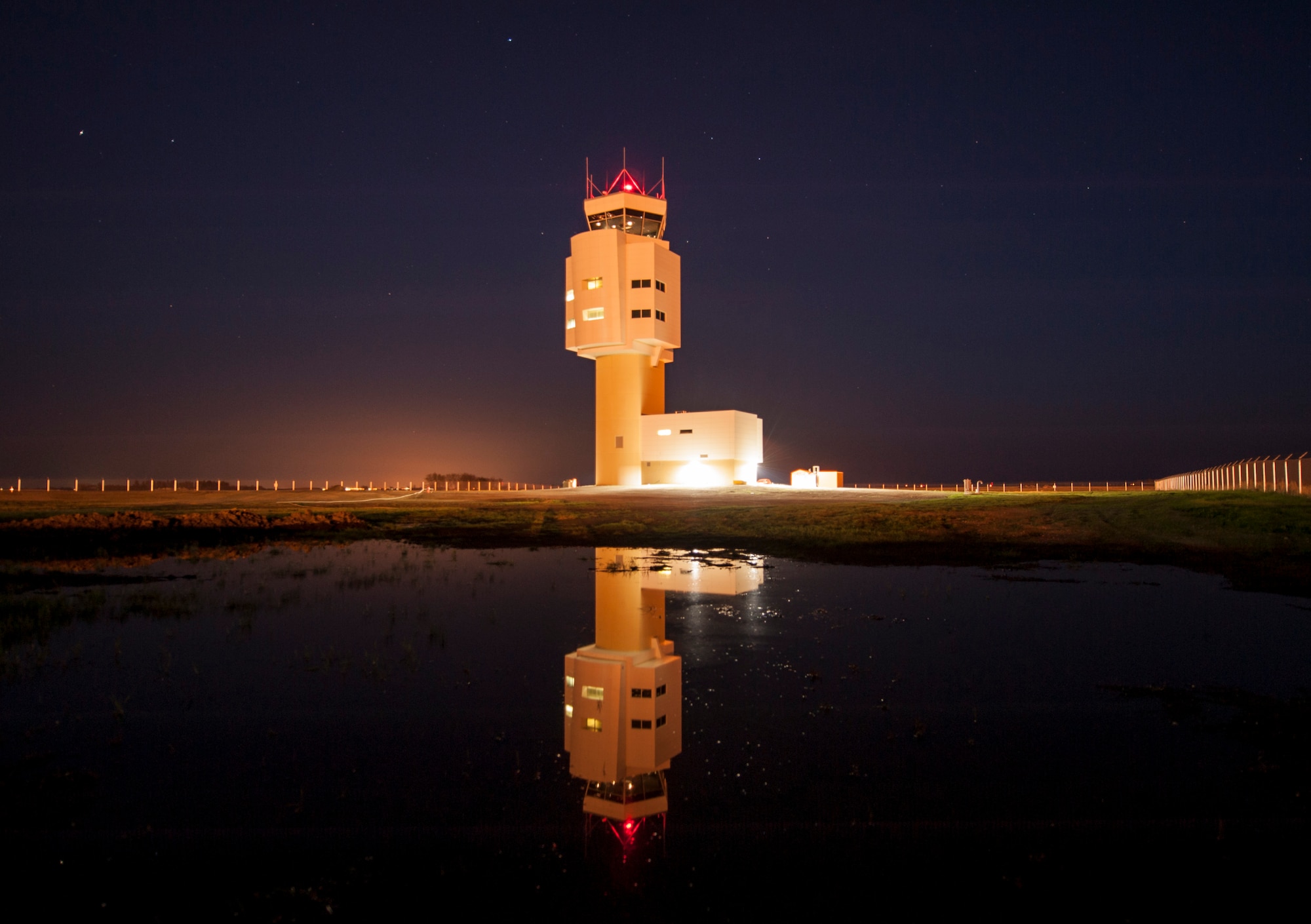 The Air Traffic Control Tower is reflected in a large puddle after heavy rain on Minot Air Force Base, N.D., May 20, 2014. The current lull in flight line operations, due to runway construction, has allowed Minot’s air traffic controllers to refocus on training. (U.S. Air Force photo/Senior Airman Stephanie Morris)