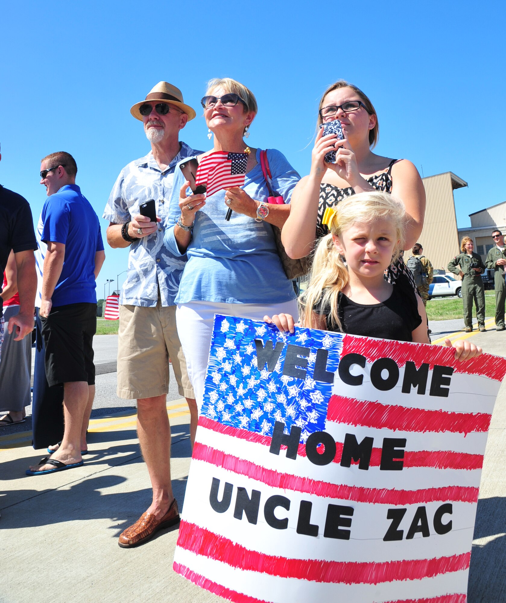 A family awaits the arrival of their loved one during Operation Homecoming on the flightline at Hurlburt Field, Fla., July 4, 2014. Families and friends greeted returning deployers as soon as they disembarked the aircraft. (U.S. Air Force photo/Senior Airman Desiree W. Moye)