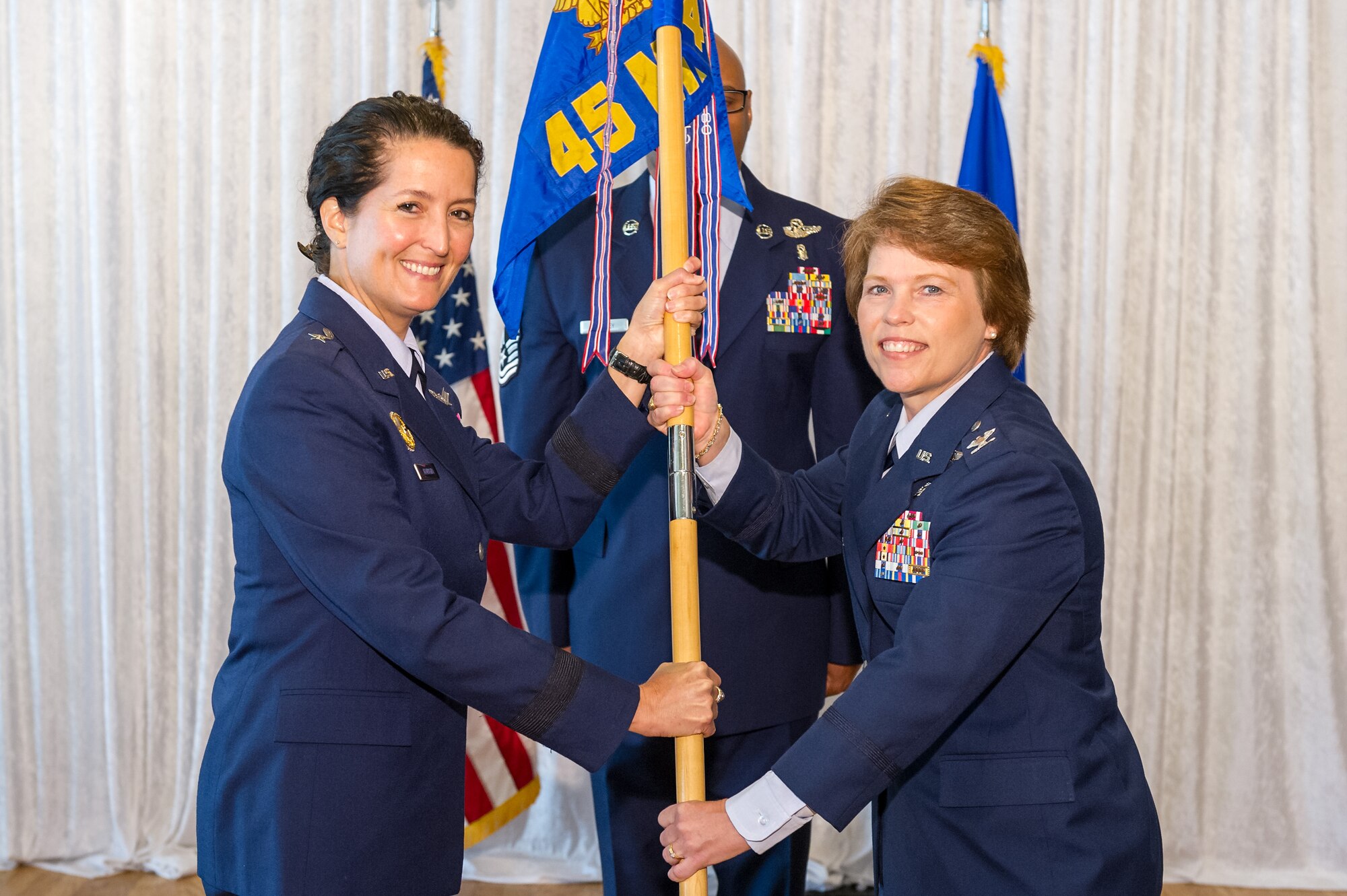 Brig. Gen. Nina Armagno, 45th Space Wing commander, left, presents Col. Julie Stola, 45th Space Wing Medical Group commander, with the 45th MDG guidon during a change of command ceremony July 3, 2014, at Patrick Air Force Base, Fla. Changes of command are a military tradition representing the transfer of responsibilities from the presiding officials to the upcoming official. (U.S. Air Force photo/Cory Long)