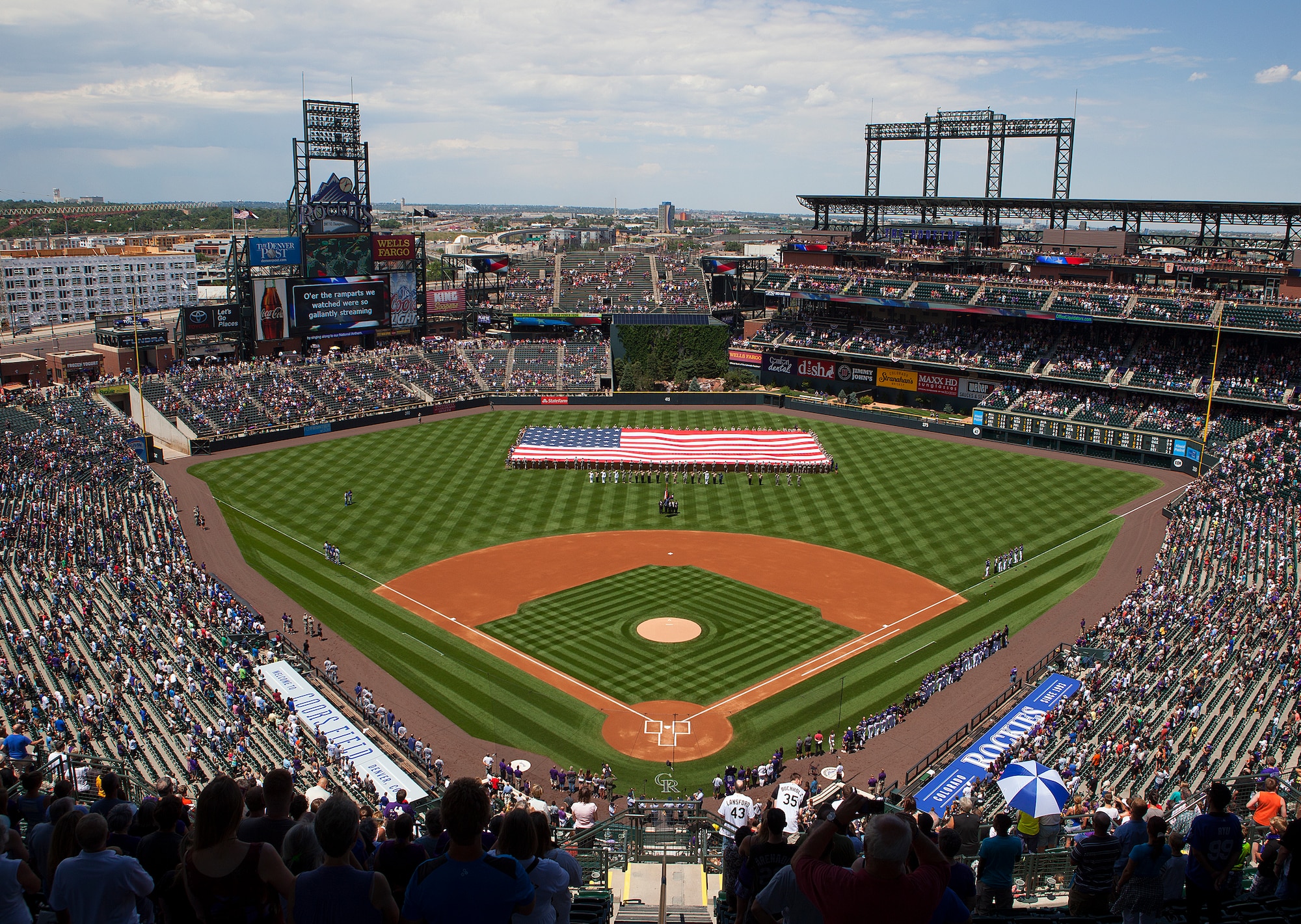 140706-F-JW097-012 Volunteers servicemen and women line the sides of a 100 by 75-foot flag during the National Anthem before a Colorado Rockies game in Denver, Colo. Marines, Soldiers, Airmen, Sailors, Coast Guardsmen and retirees came together for the ceremony honoring the military and veterans before the game. (U.S. Air Force photo by RJ Oriez)