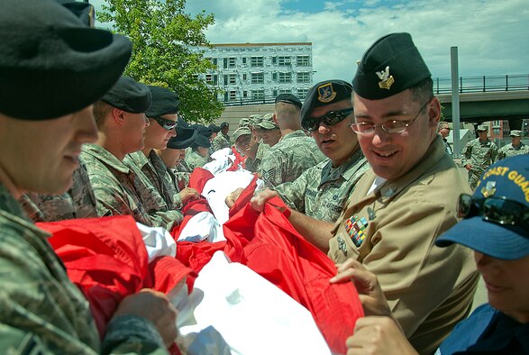 140706-F-GZ967-020 Volunteers take positions around an 100 by 75-foot flag July 17 as they prepare to participate in a flag unfurling ceremony before a Colorado Rockies game in Denver, Colo. More than 150 military personnel volunteered their time to participate in the ceremony. (U.S. Air Force photo by Airman 1st Class Brandon Valle)