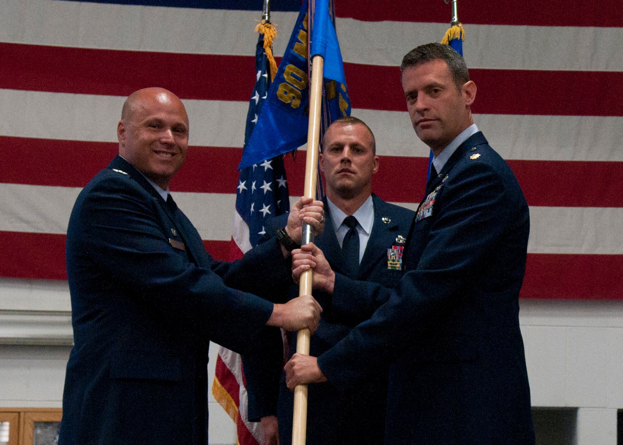 Col. Travis Condon, 90th Mission Support Group commander, passes the 90th LRS guidon to Maj. Shawn Booher as he assumes command of the squadron during a change-of-command ceremony in the Vehicle Maintenance High Bay on F.E. Warren Air Force Base, Wyo., July 7, 2014. (U.S. Air Force photo by Airman Malcolm Mayfield)
